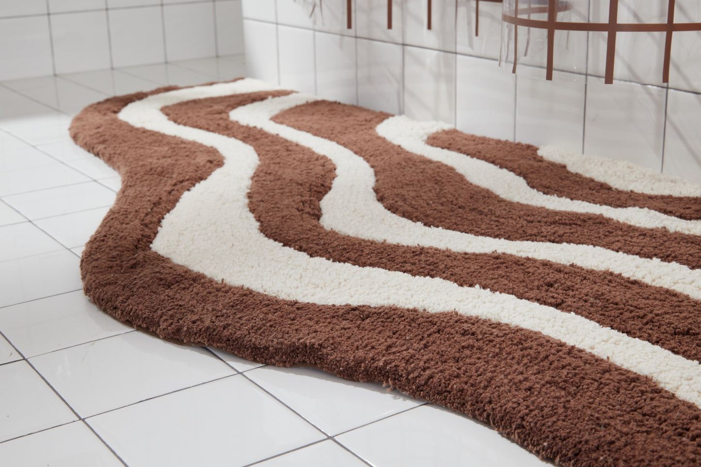 Close up side shot of lost coast bath mat in chocolate in white tiled bathroom.