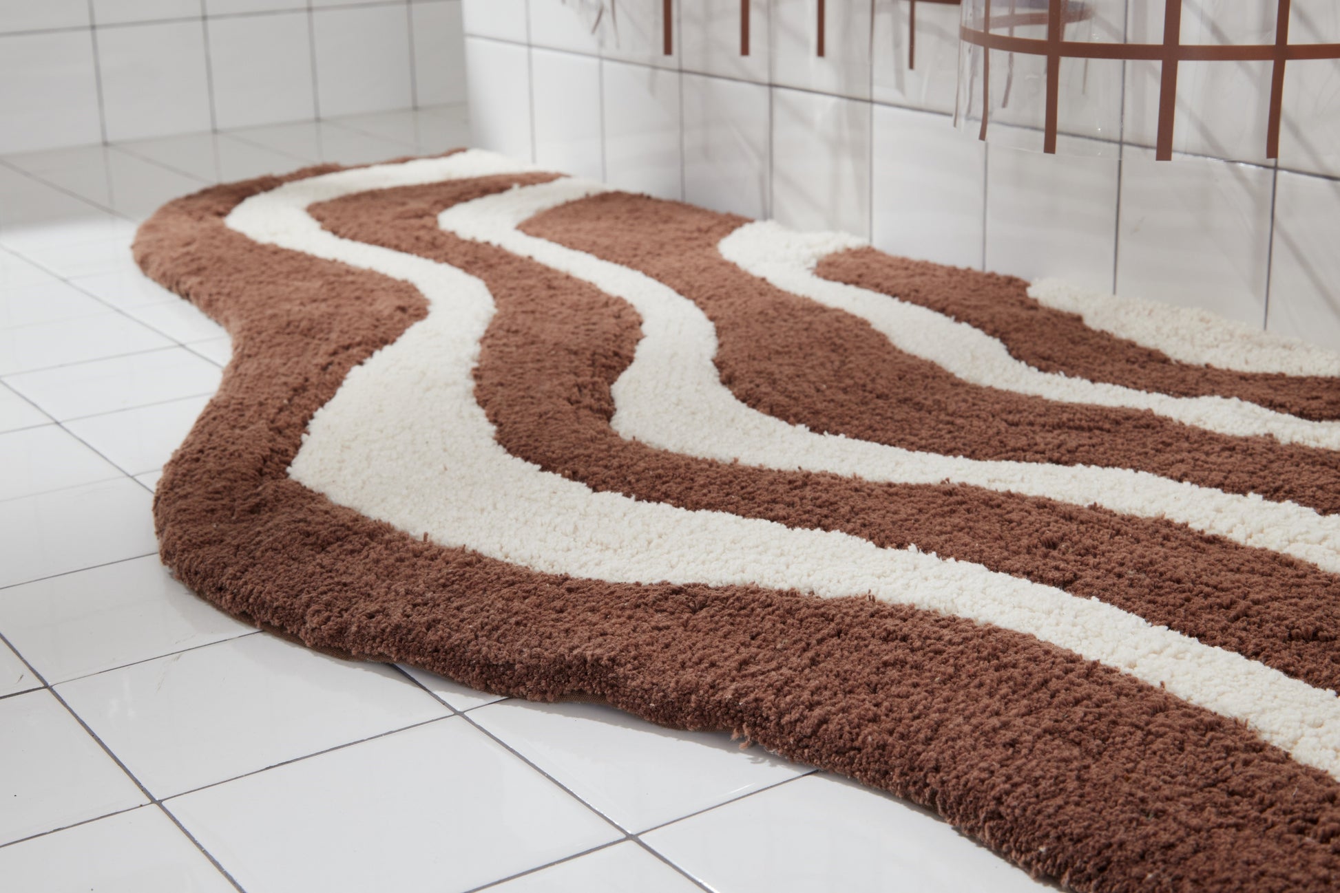 Close up side shot of lost coast bath mat in chocolate in white tiled bathroom.