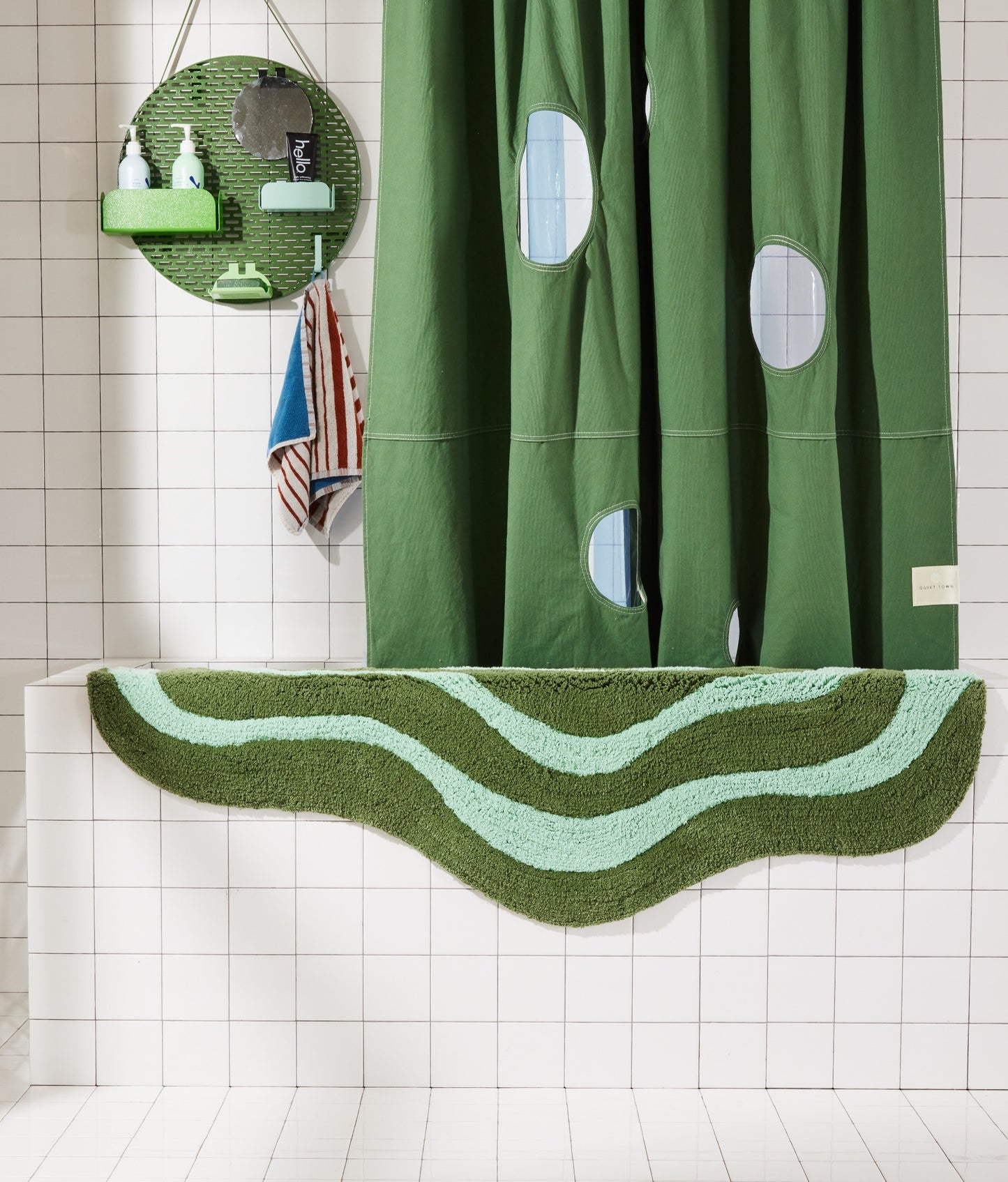 Wave shaped pine and jade striped bath mat runner in 56"x22" size hanging over side of white tiled bathtub.