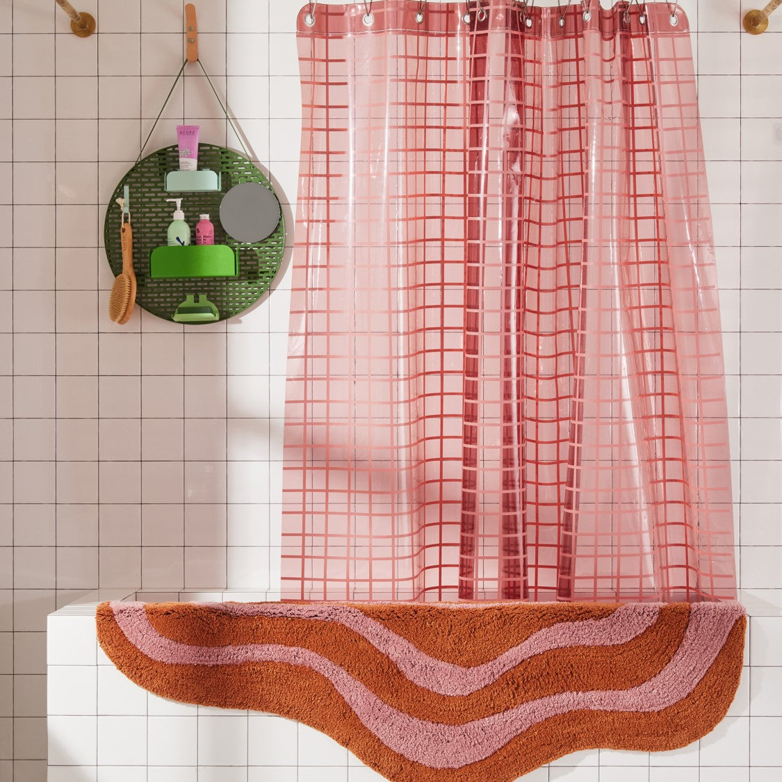 Wave shaped honey and rose striped bath mat runner in 56"x22" size hanging over side of white tiled bathtub.