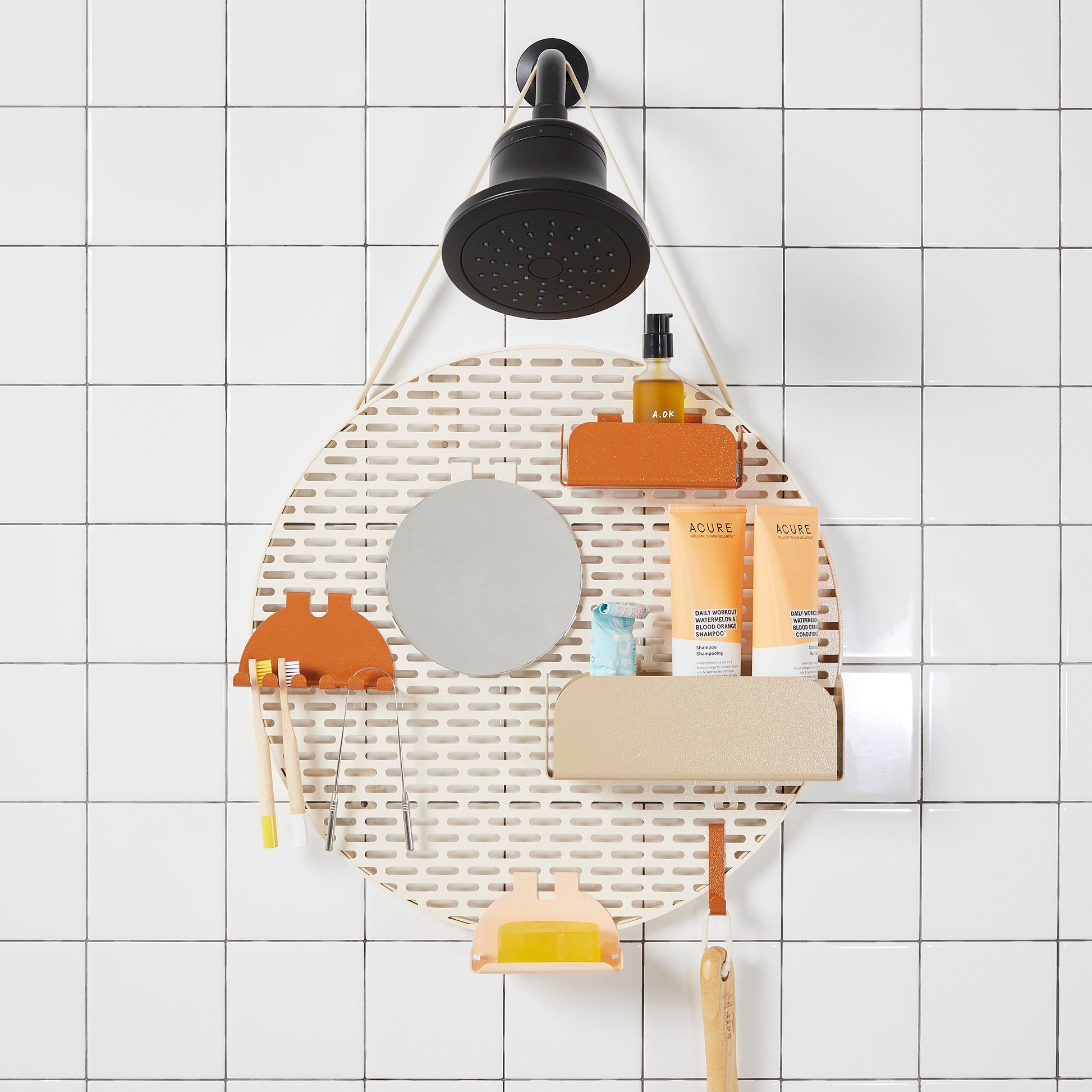 The spot modular shower organizer with shelving pieces arranged and holding products, hanging in a white tiled shower.