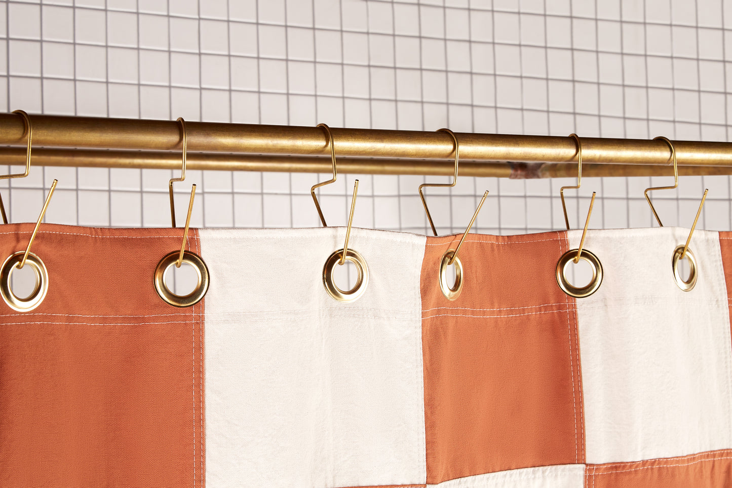 Re:Canvas Checker Clay detail view of grommets and hooks hanging from shower curtain rod.