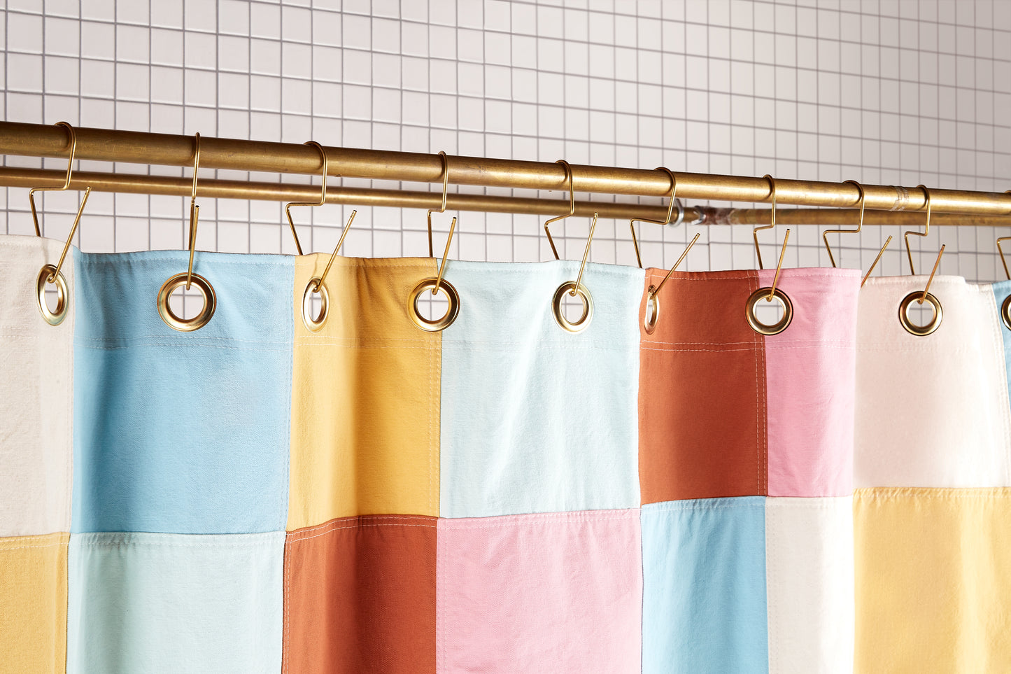 Re:Canvas Checker Deco detail view of grommets and hooks hanging from shower curtain rod.