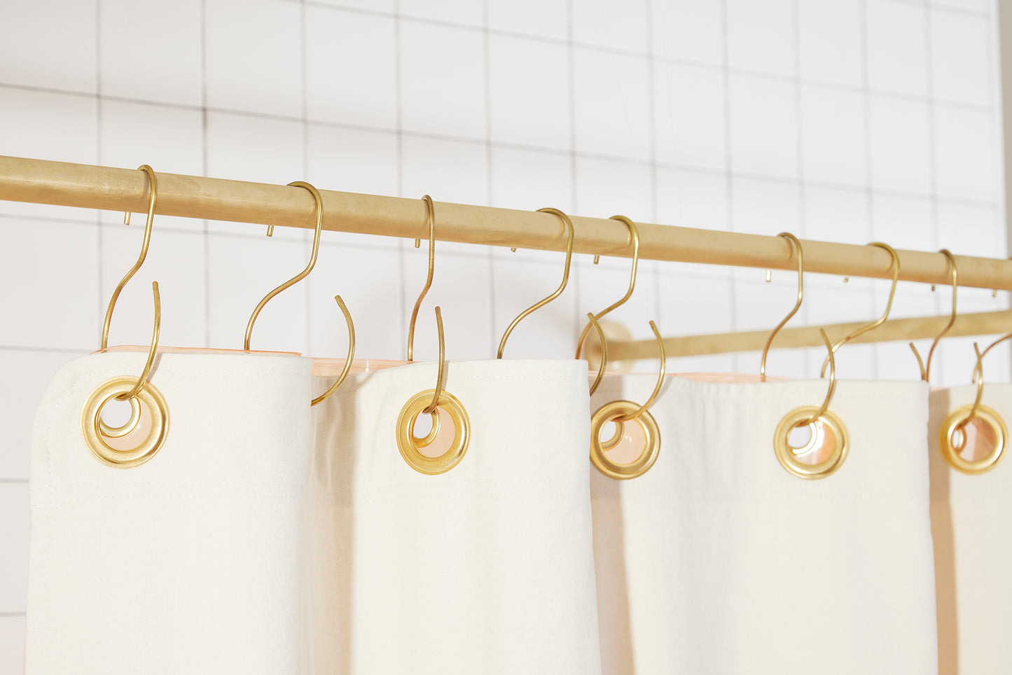 Orient Pine detail view of grommets and hooks hanging from shower curtain rod.