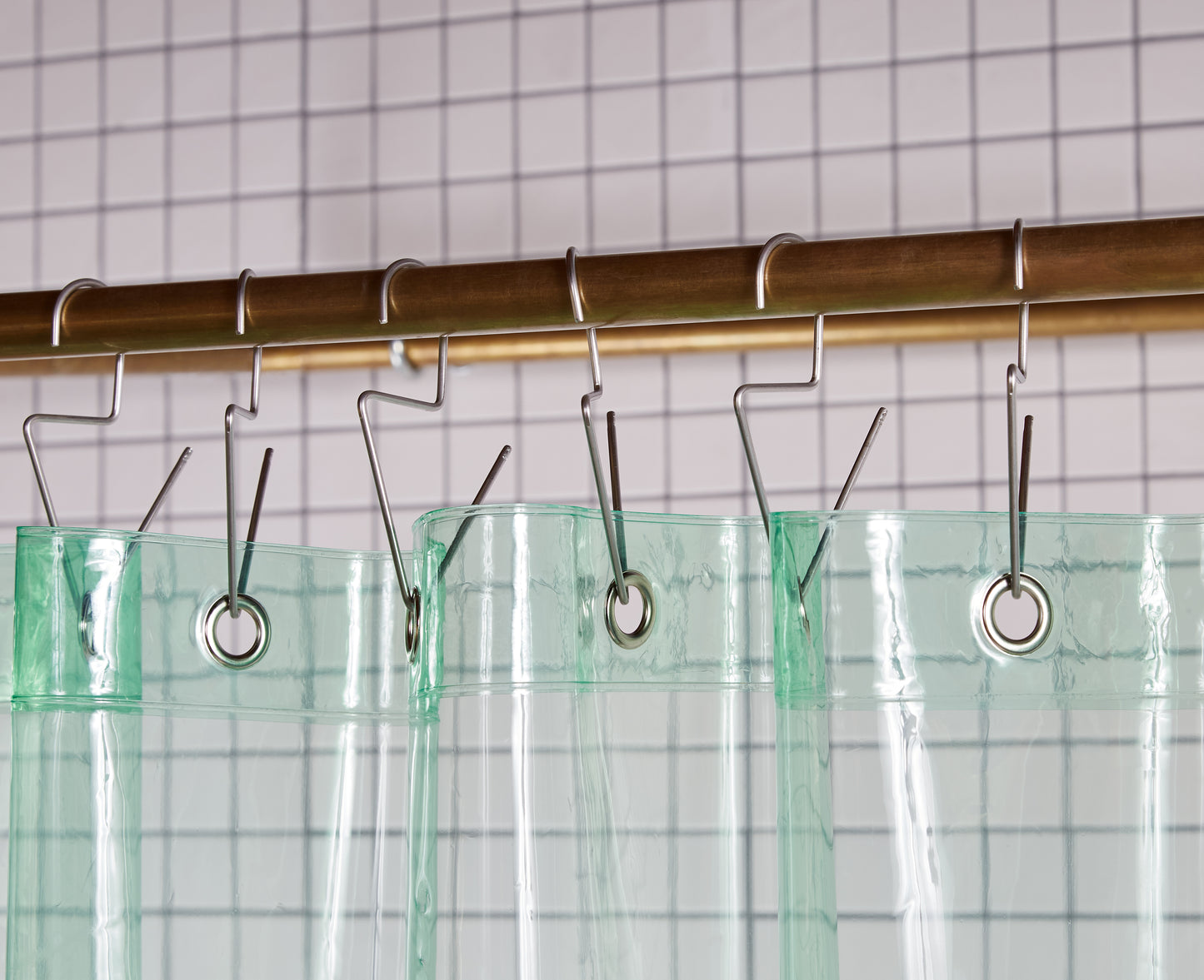 Sun Shower High view of grommets and hooks hanging from shower curtain rod.