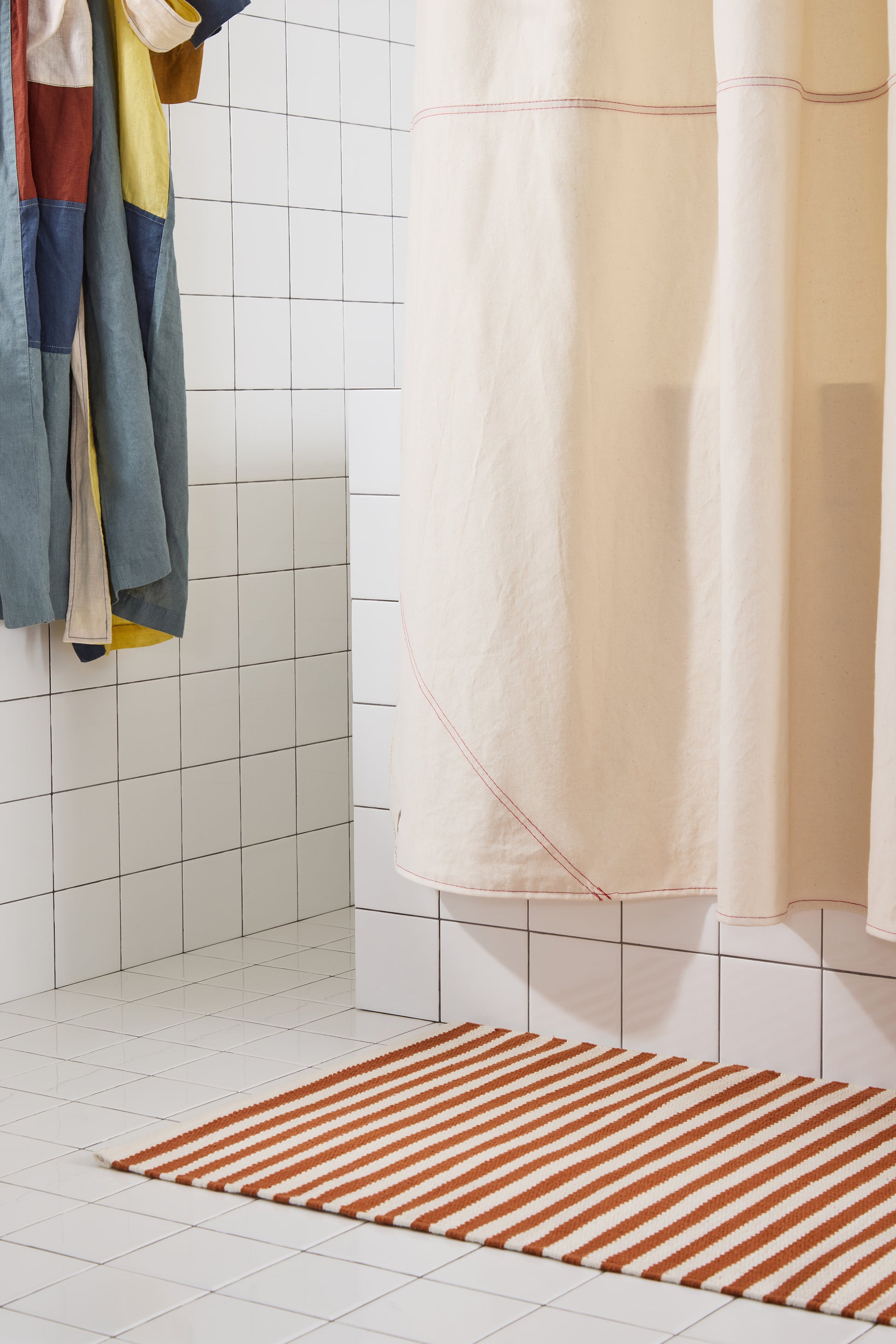 corner of cream canvas curtain and red striped rug. 