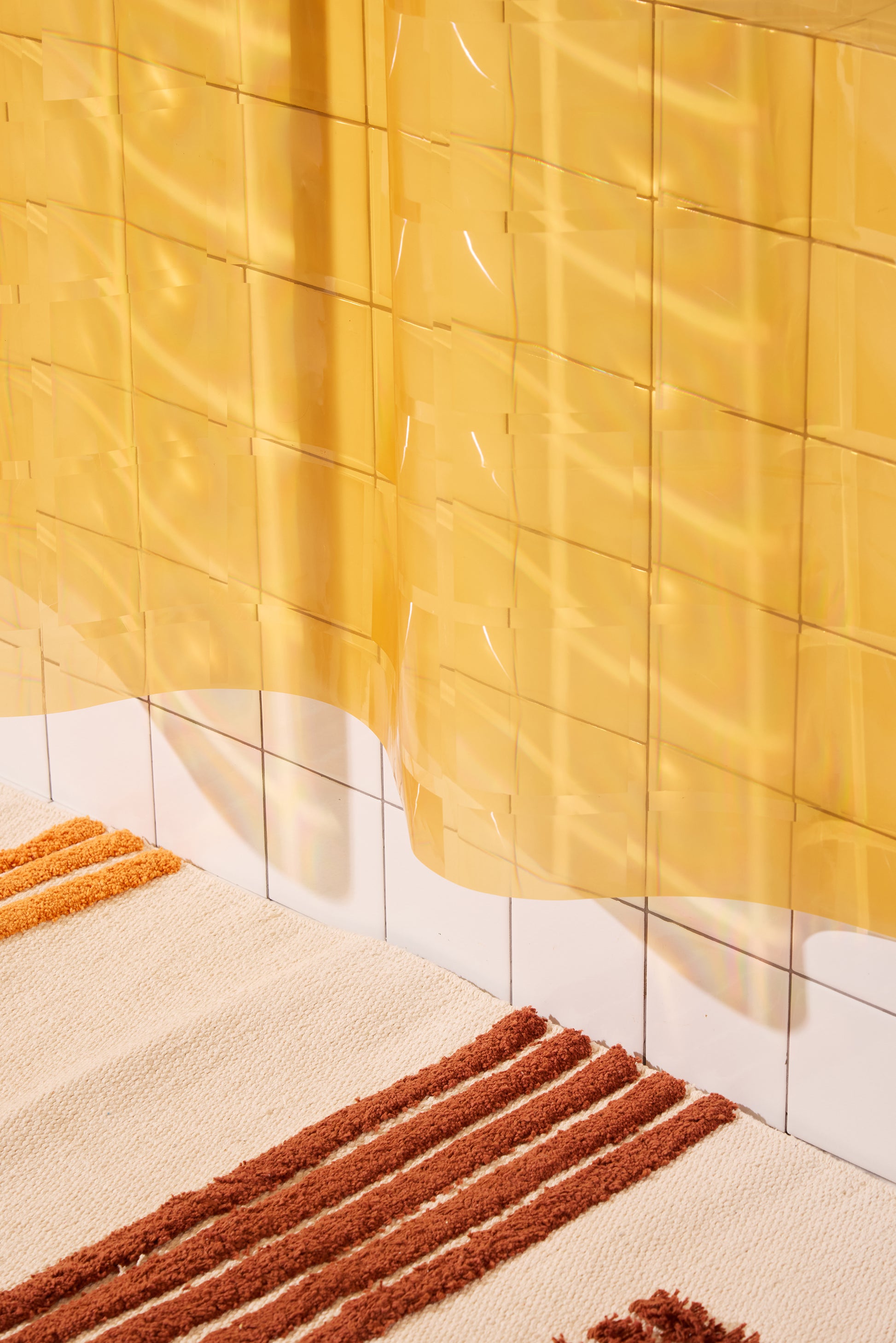 Close-up of yellow shower curtain with a textured rug. 