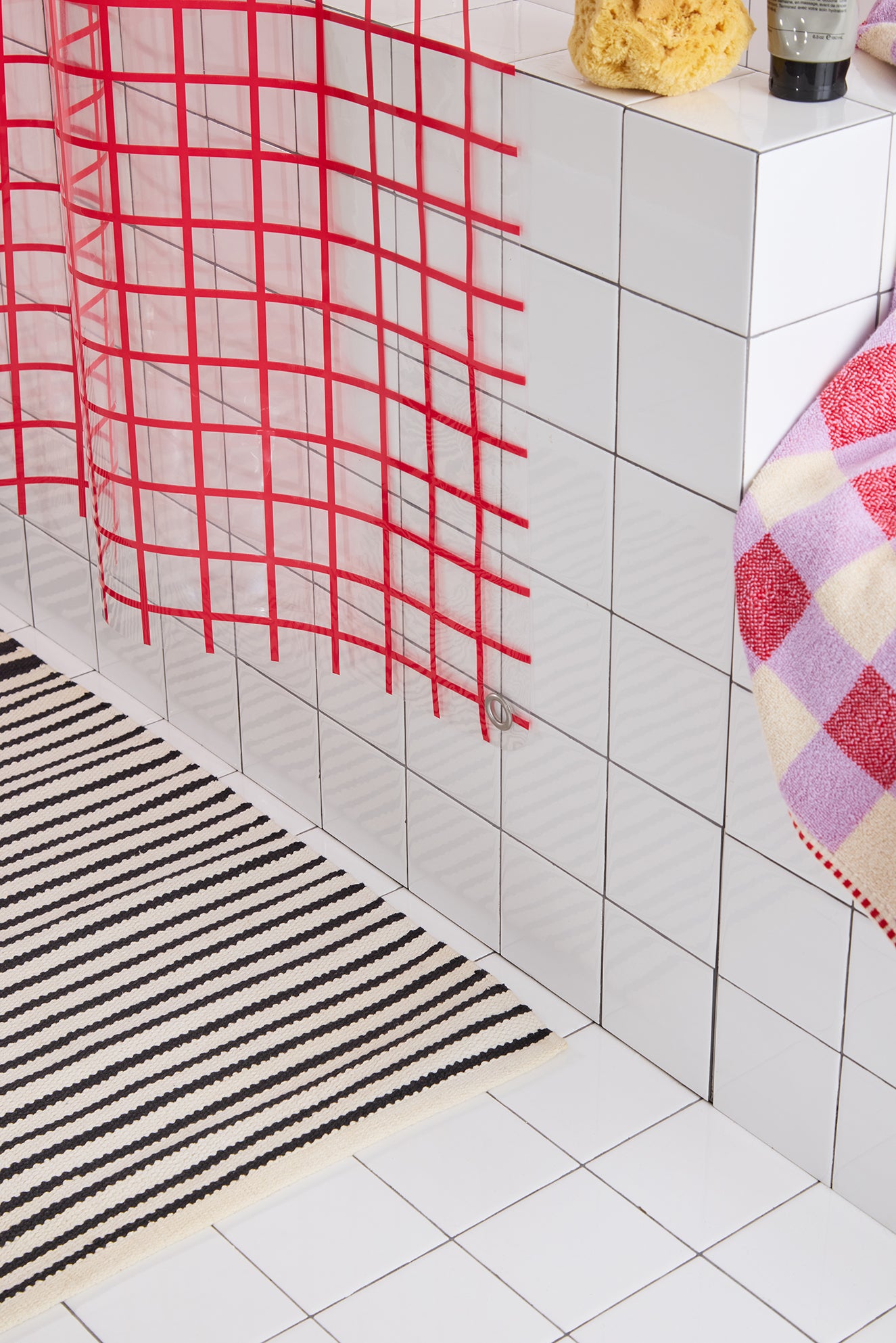  red grid curtain, black and white striped rug, and colorful towel.