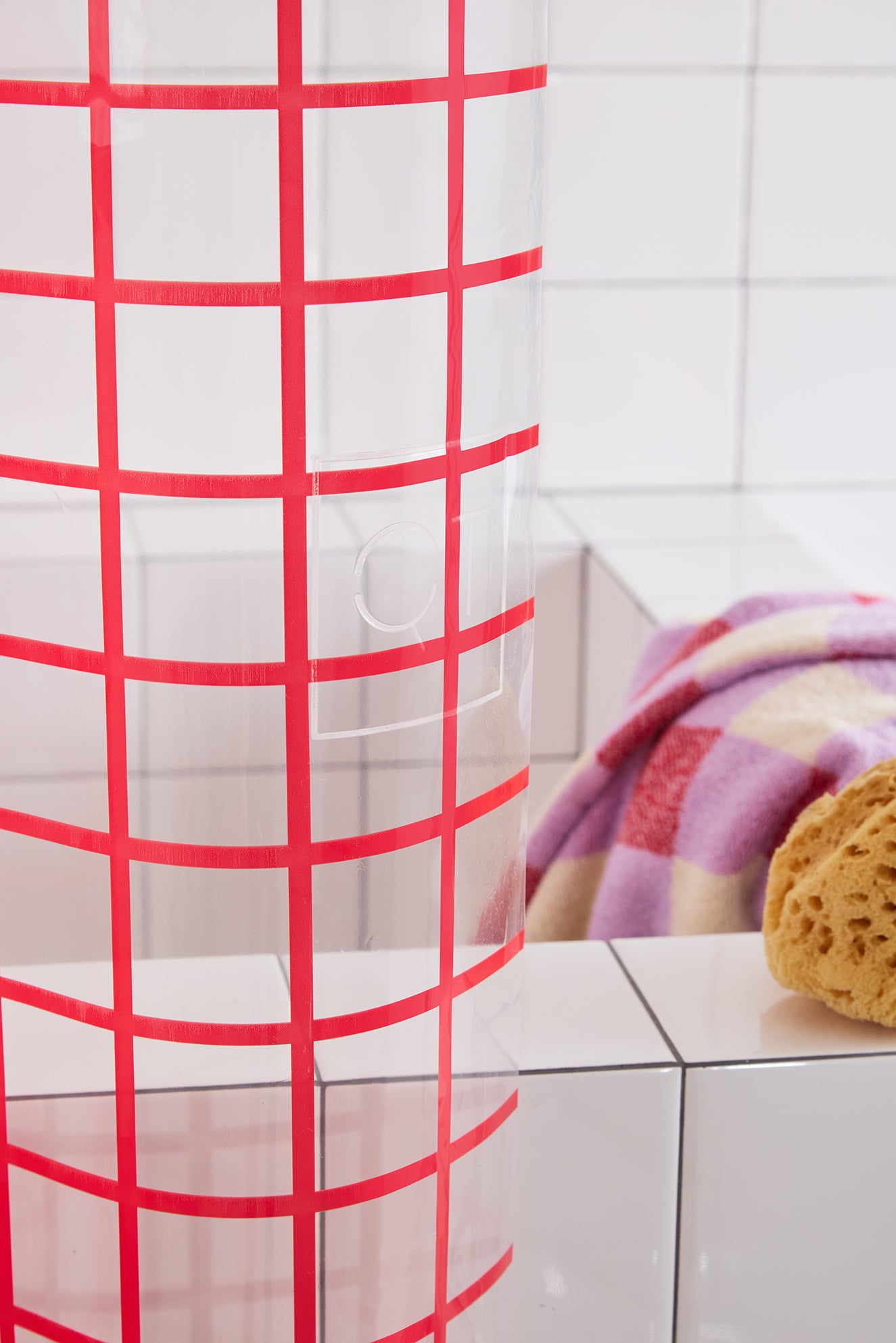 Red grid shower curtain with a bathtub and towel in the background