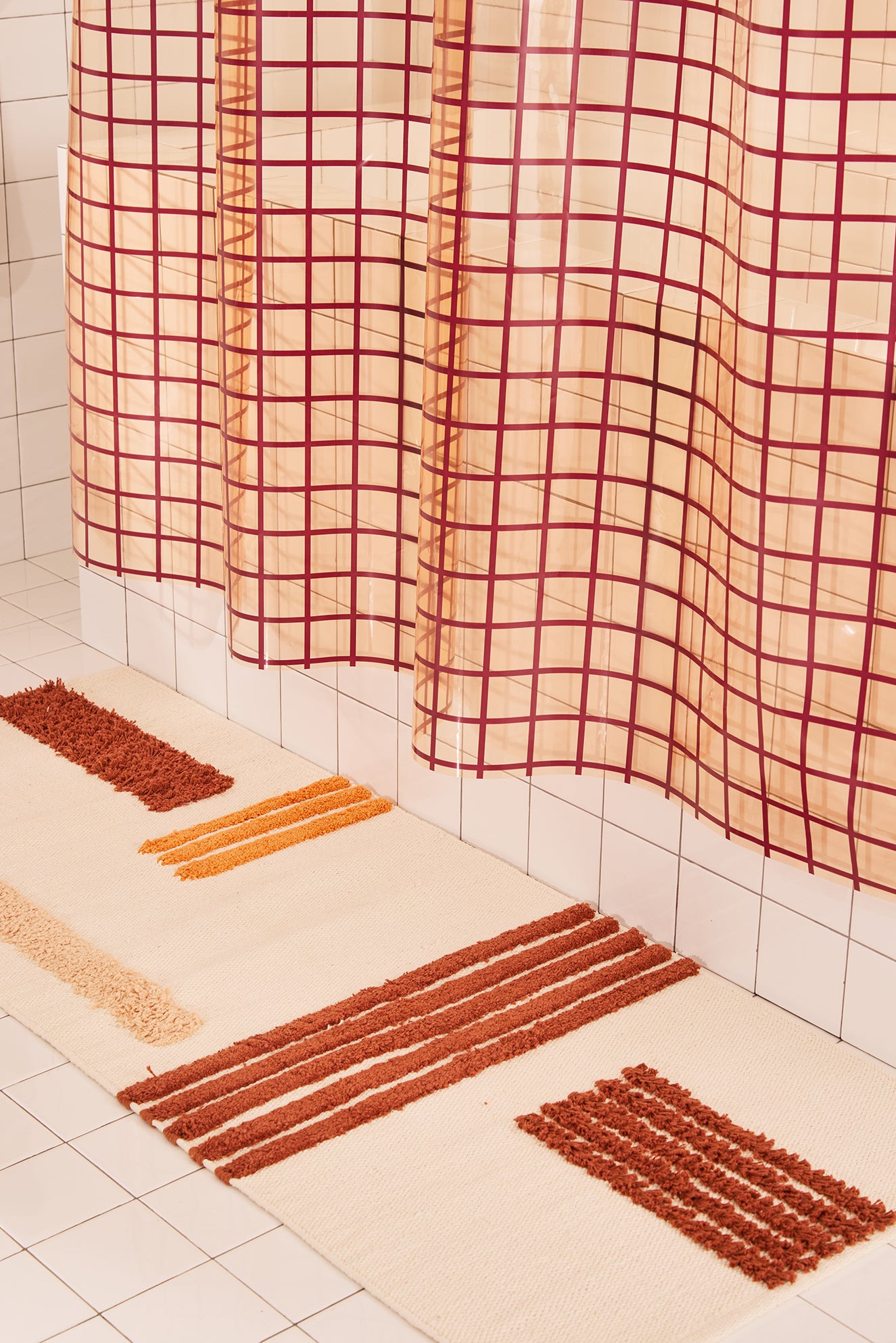 Bathroom with checkered shower curtain and bath mats on tiled floor