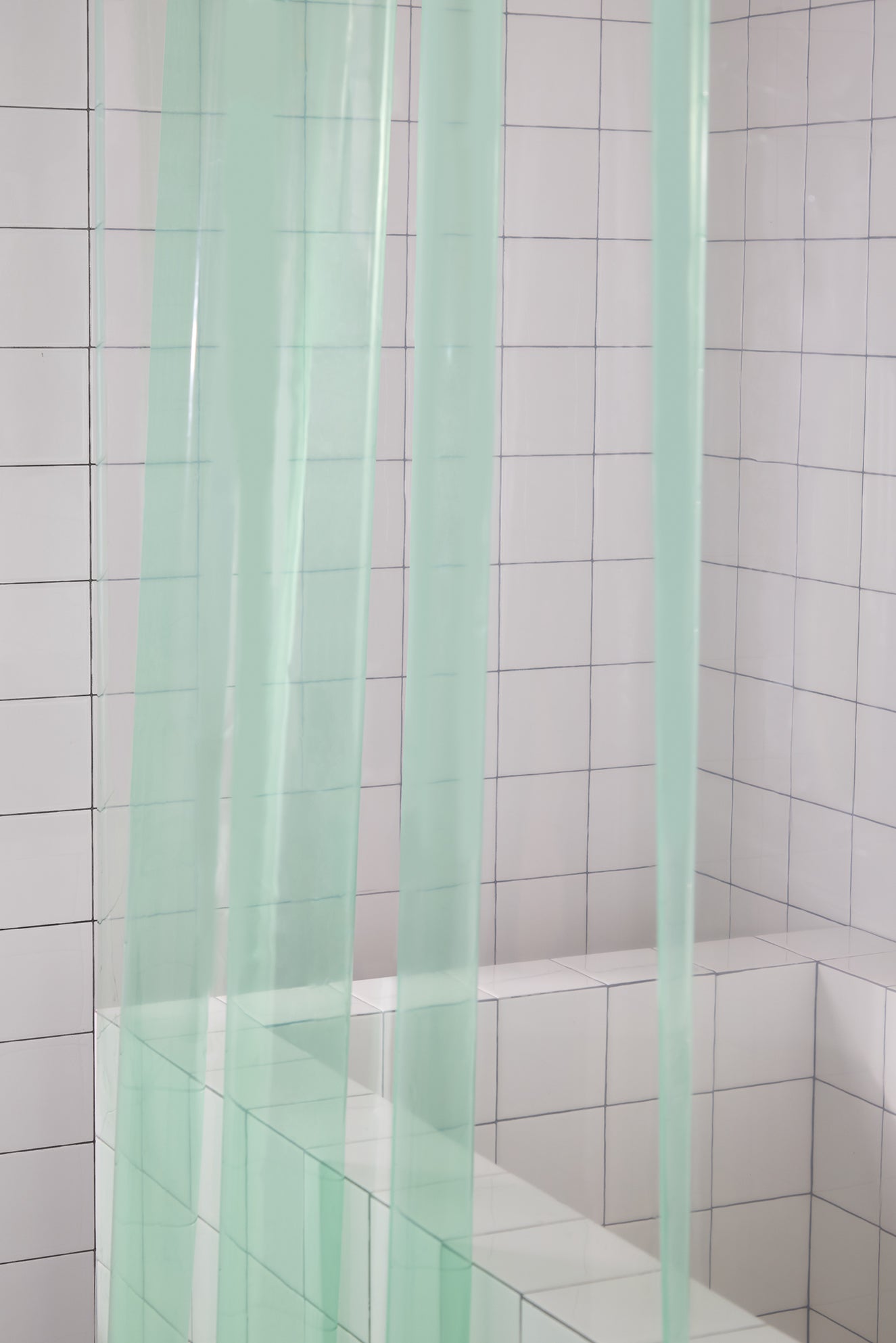 Green shower curtain in a tiled bathroom