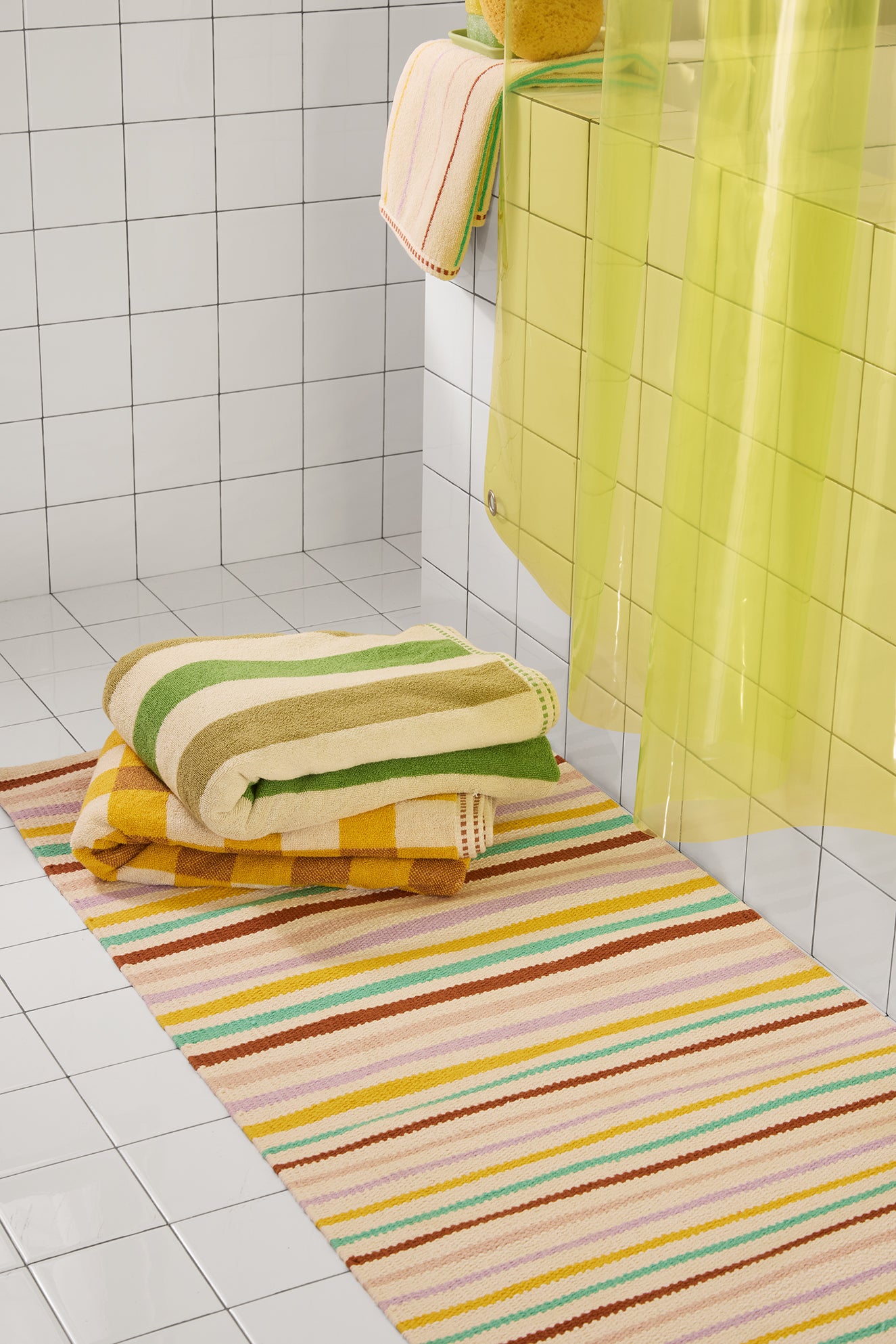 Striped bath mat with towels on a tiled bathroom floor