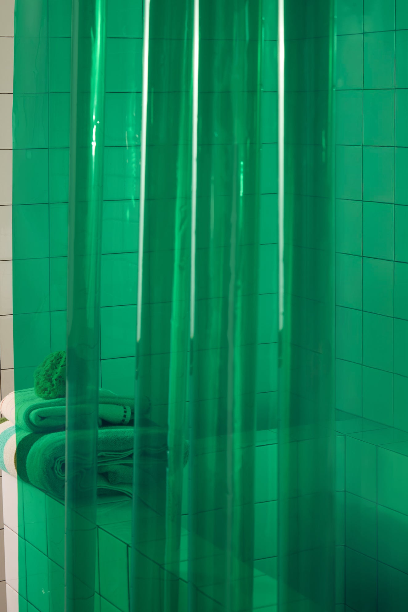 Green shower curtain with tiled walls in a bathroom setting