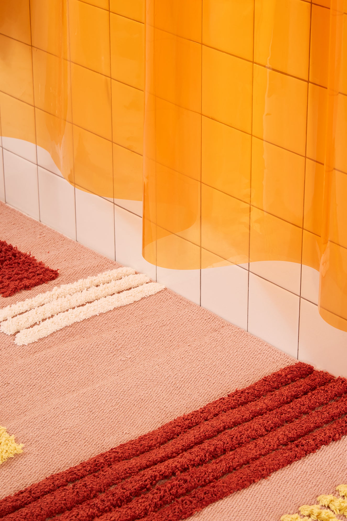 Close-up of a textured rug with orange curtain in the background
