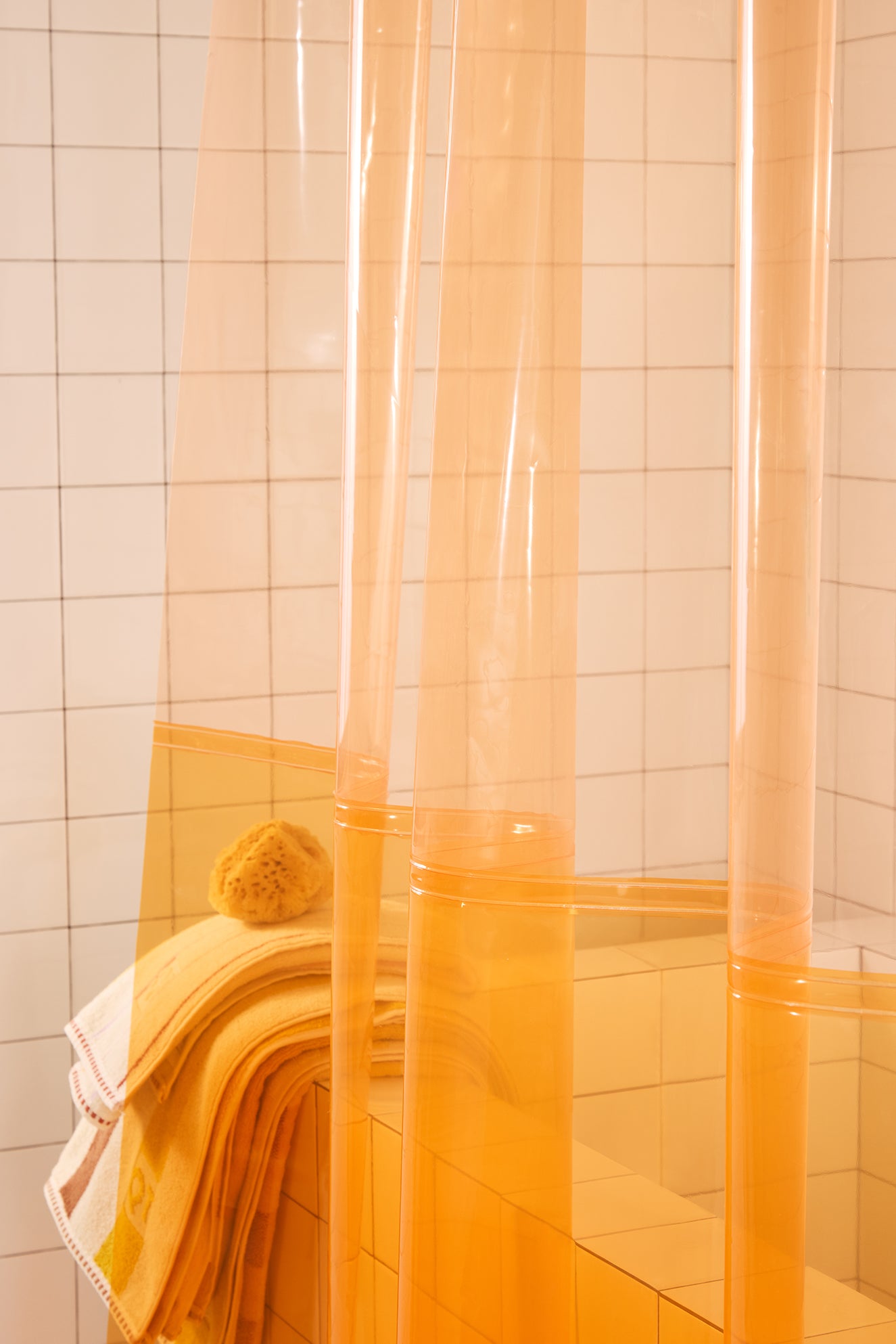 Orange shower curtain in a tiled bathroom.
