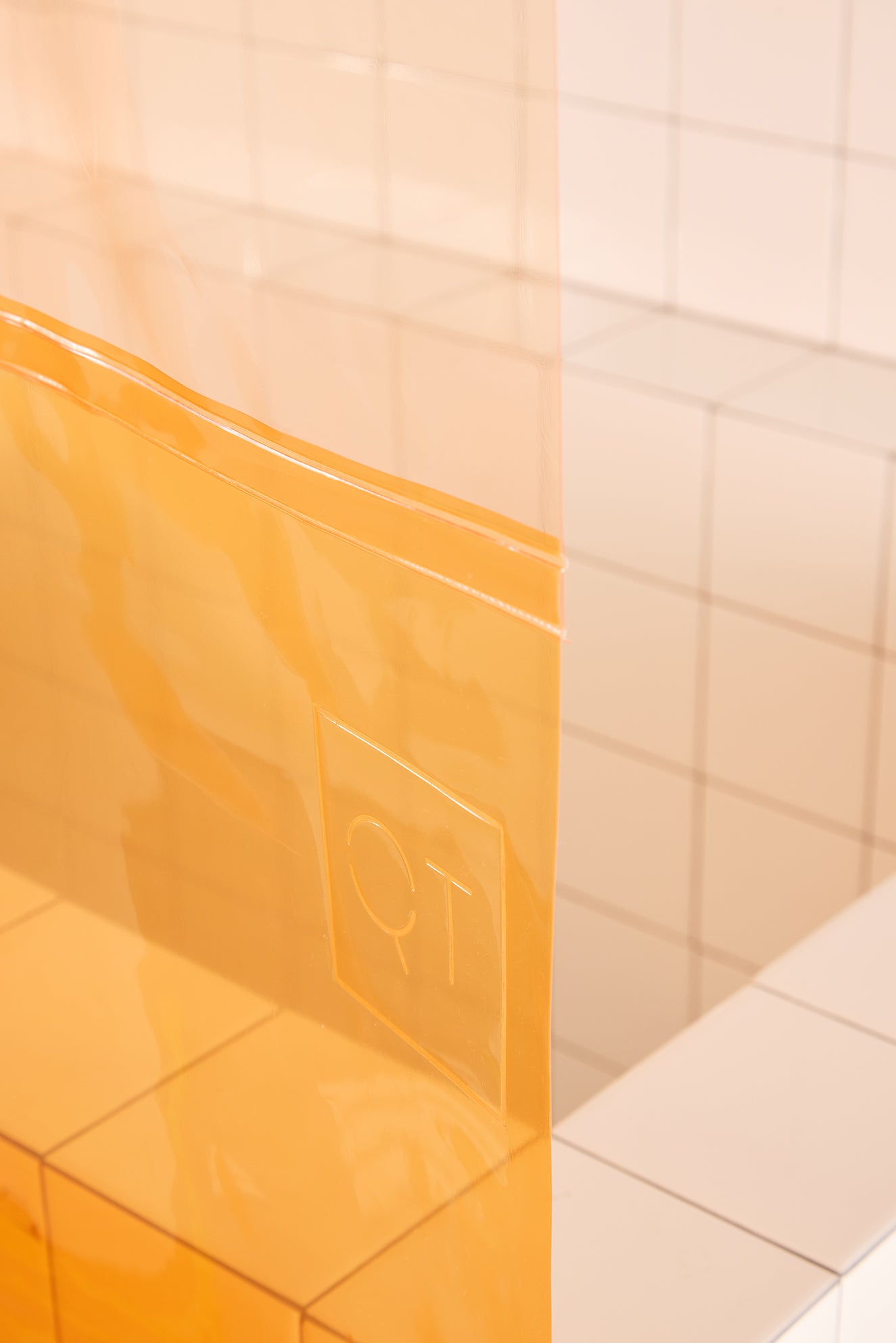 Orange plastic curtain with a QT logo on a tiled floor