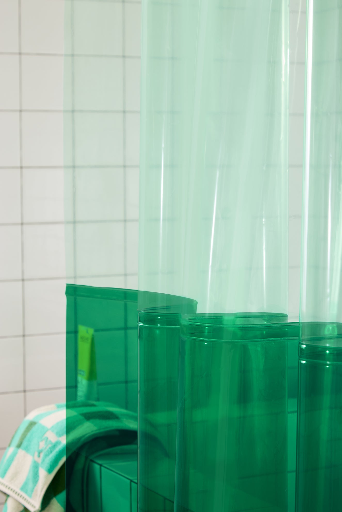 Green plastic shower curtain with a tiled bathroom background