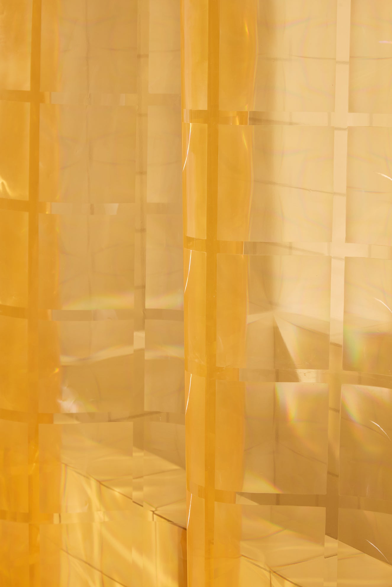 Close-up of a textured yellow shower curtain with geometric patterns