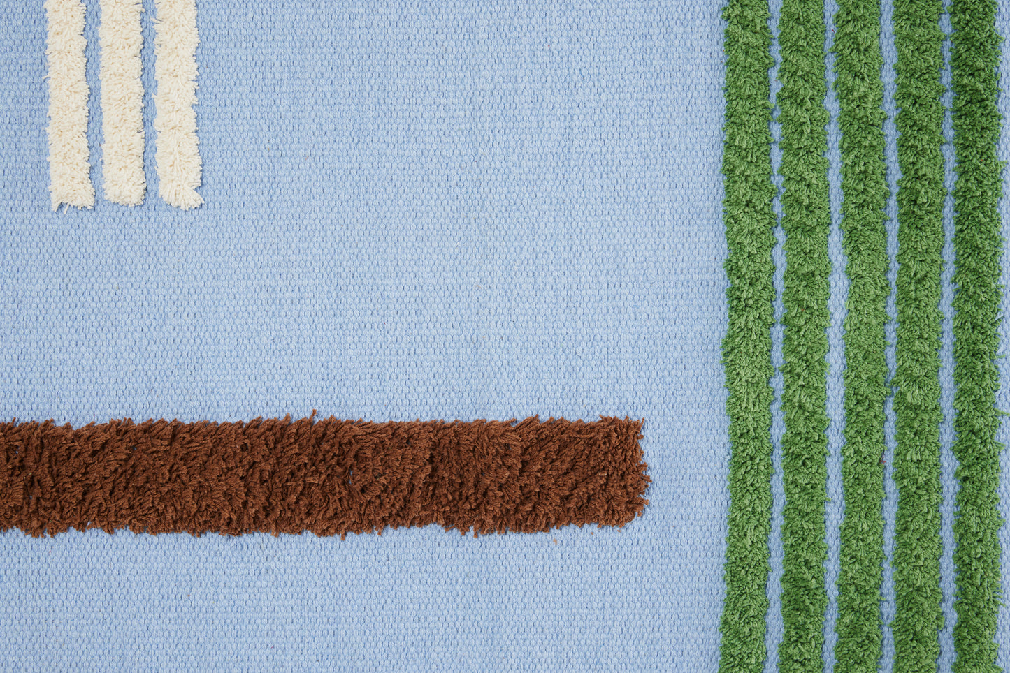 Close-up of blue rug with white, green and brown stripes.