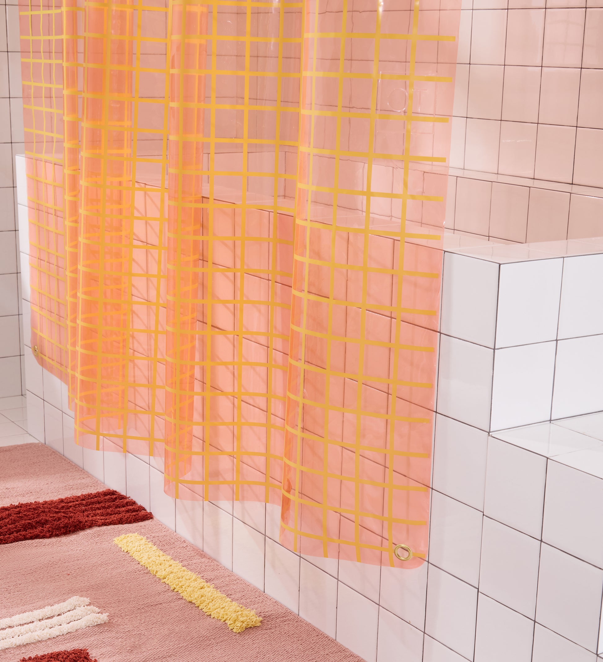 Bottom section of 2x2 grid sun shower curtain in peony hanging above rose colored reyes bath mat. 