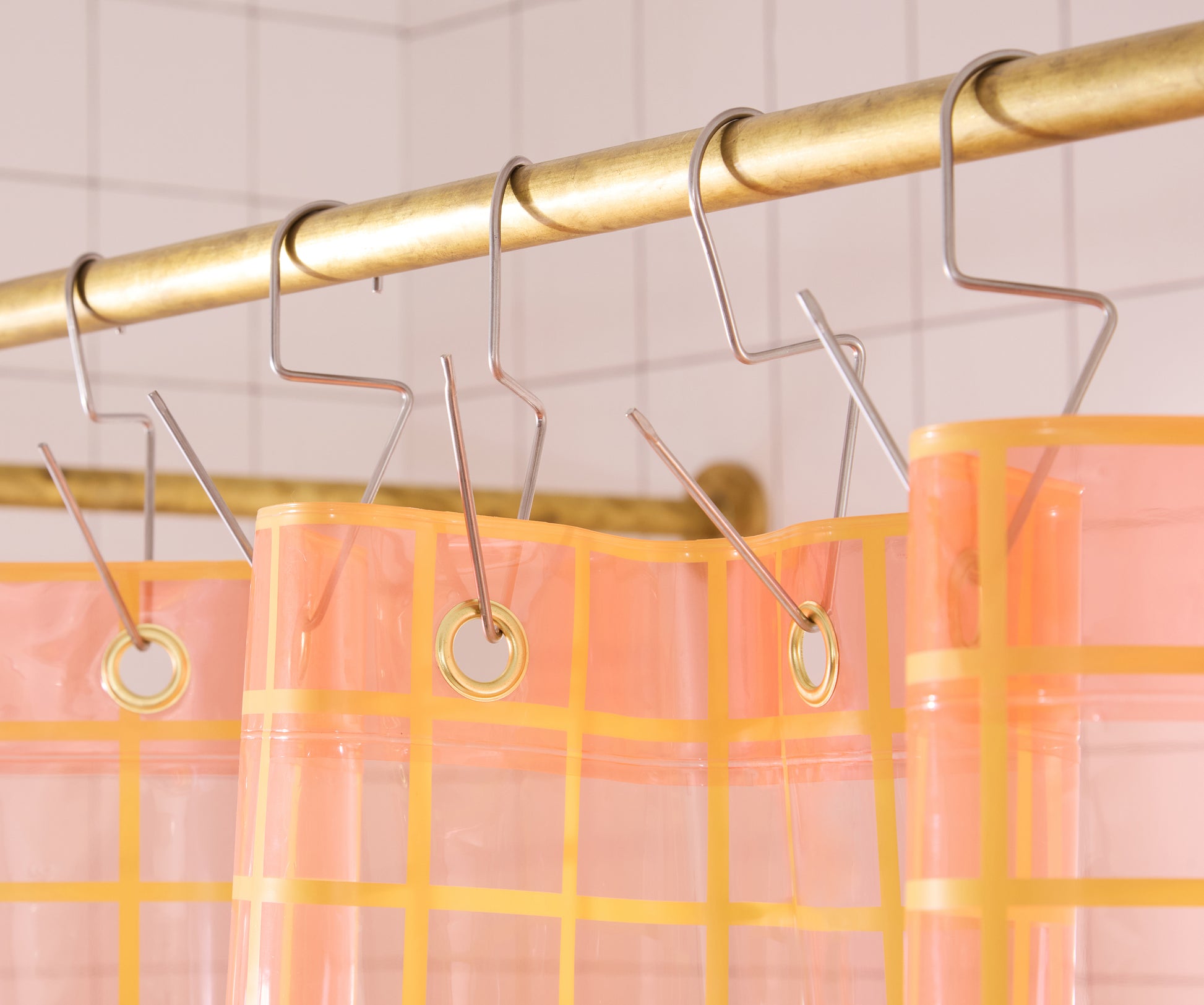 Top seam of sun shower curtain hanging on brass bar with silver venice hooks. 