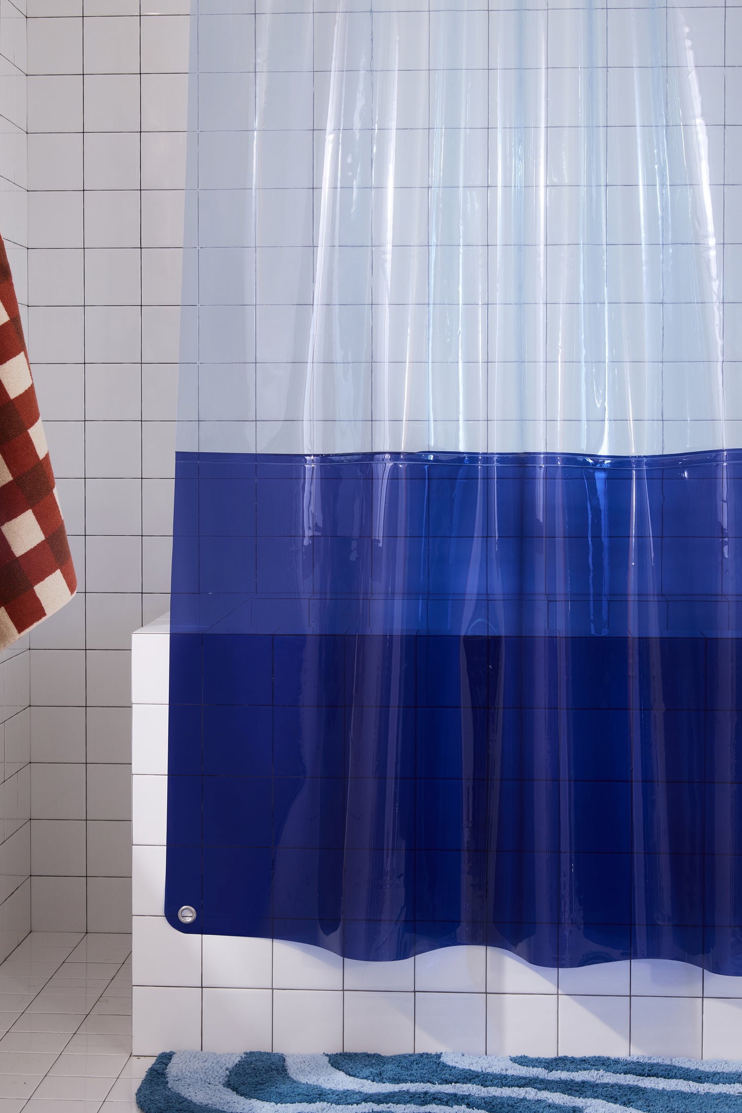 Left side of orient sun shower curtain hanging in a white tiled bathroom. 