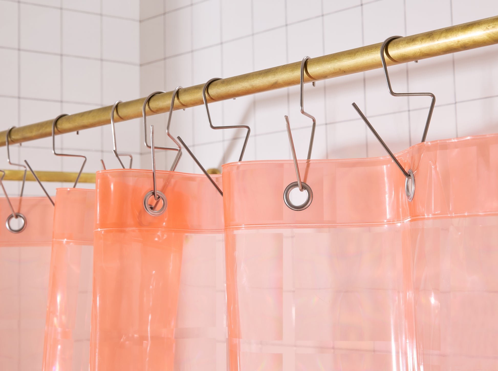 Top hem of Light pink 3D printed shower curtain hanging on brass rod. 