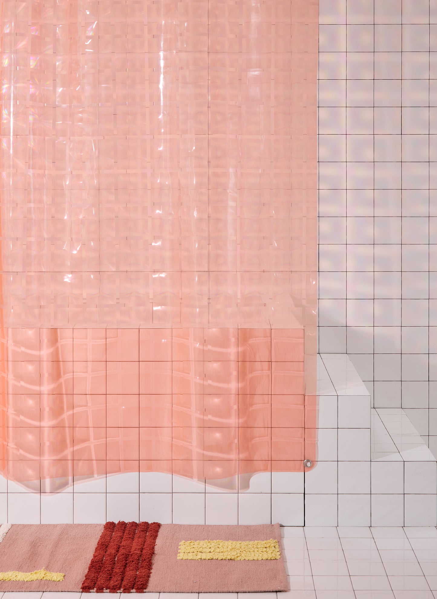 Light pink 3D printed shower curtain hanging in white tiled bathroom with rose colored rug. 