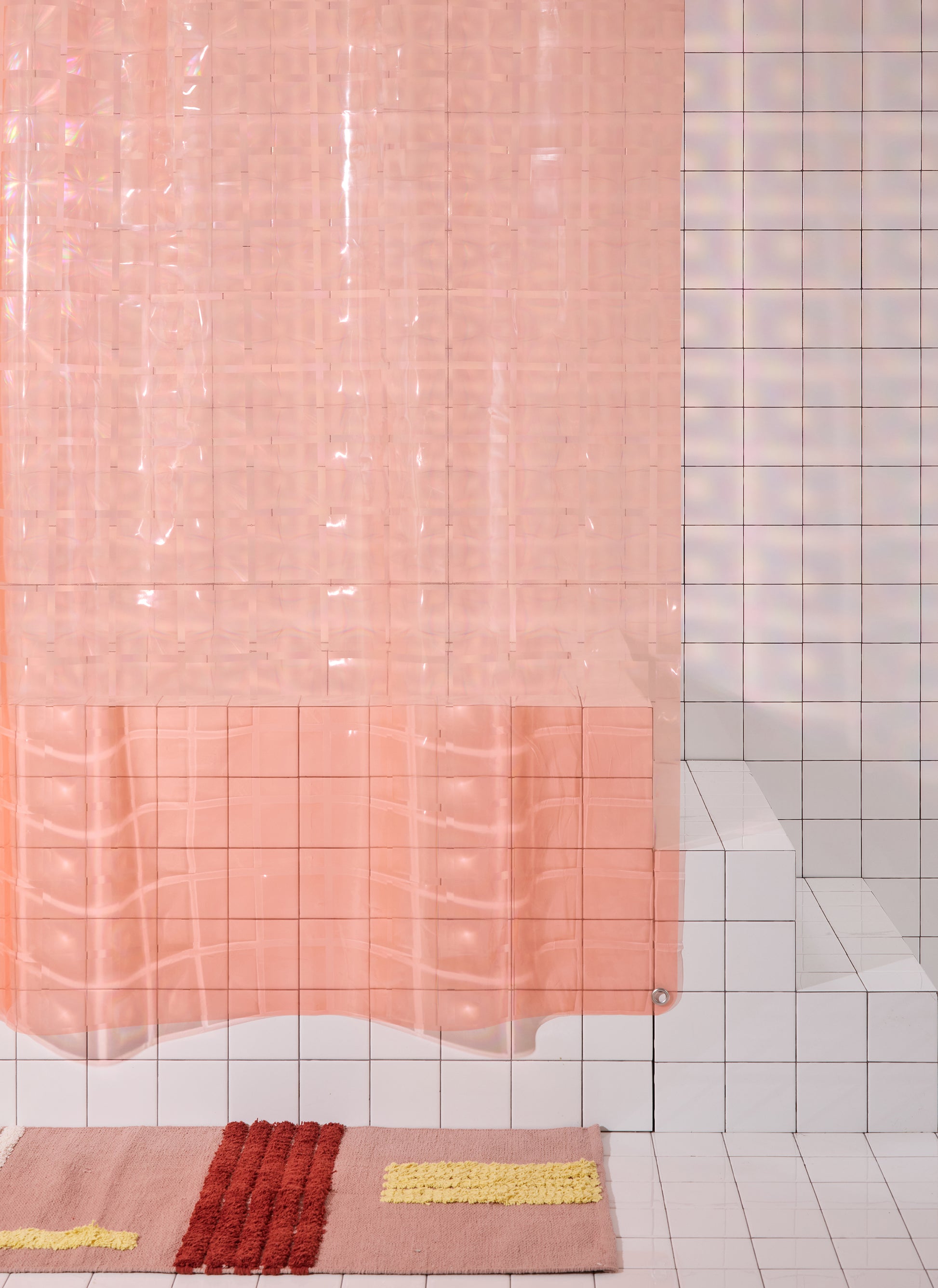 Light pink 3D printed shower curtain hanging in white tiled bathroom with rose colored rug. 