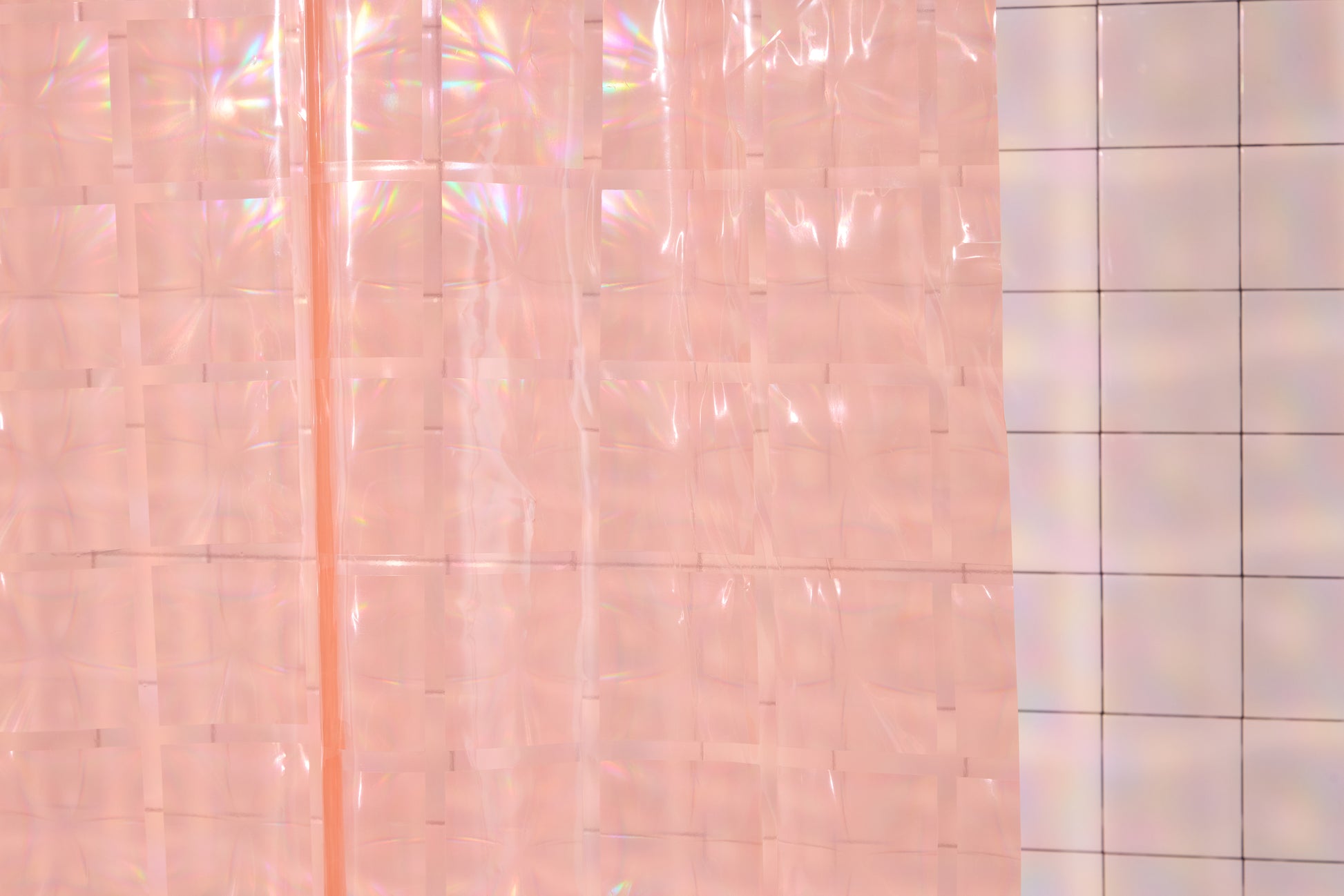 Detail of light pink 3D printed shower curtain hanging in white tiled bathroom. 