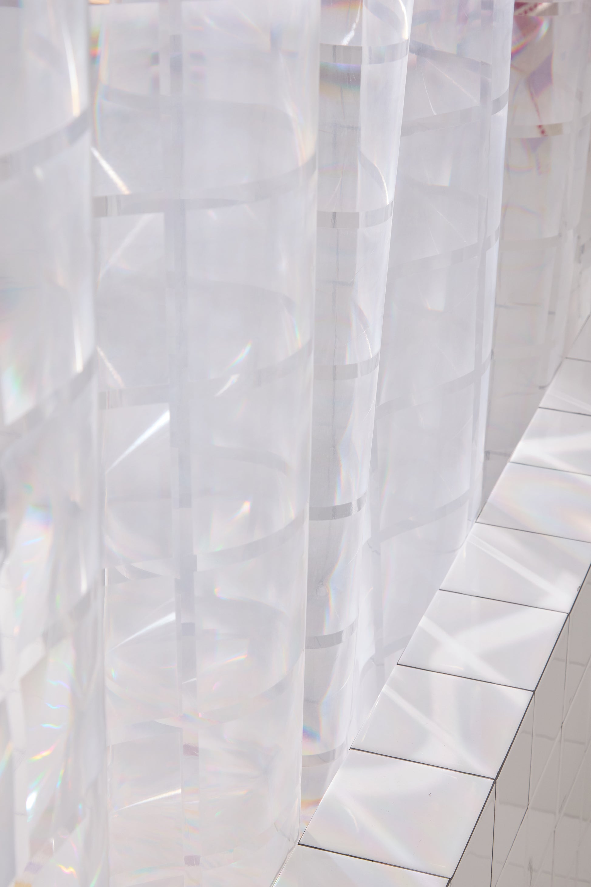 clear 3D curtain hanging in bathroom with white tile.