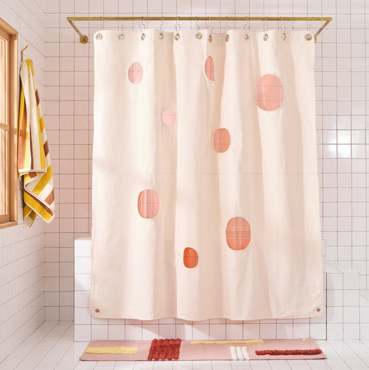 natural colored shower curtain with circular cut-outs and Peony sun shower curtain layered behind it. 
