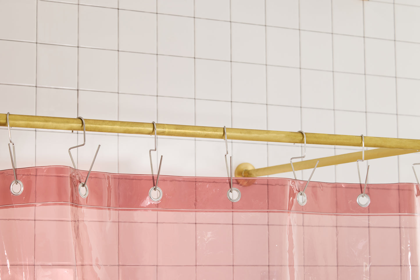 Sun Shower in Rose detail view of grommets and hooks hanging from shower curtain rod.