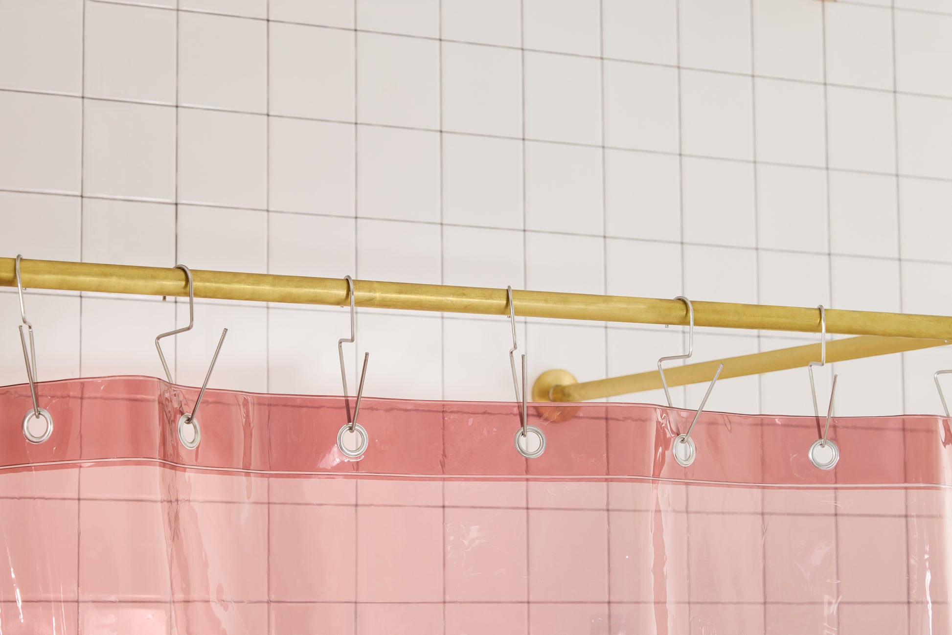 Sun Shower in Rose detail view of grommets and hooks hanging from shower curtain rod.