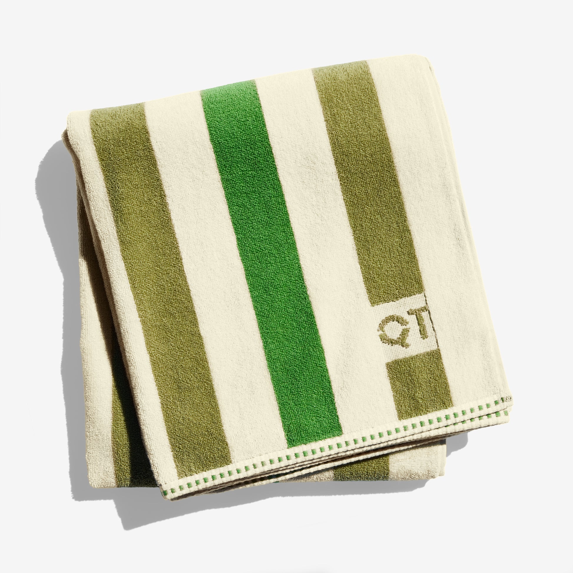 Folded towel with green and olive stripes and 'QT' branding on a white background
