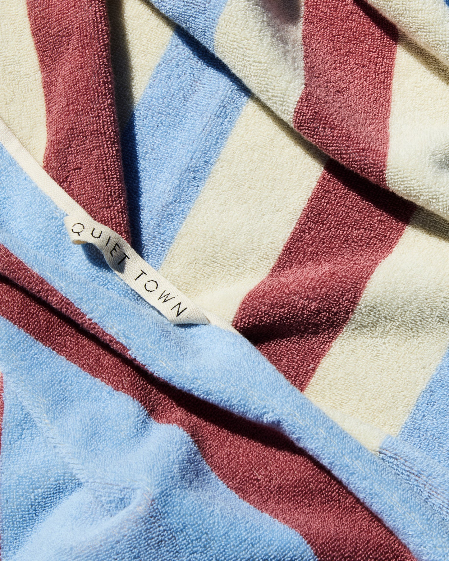 Striped blue and rose and cream towel with 'Quiet Town' hanging loop in close-up