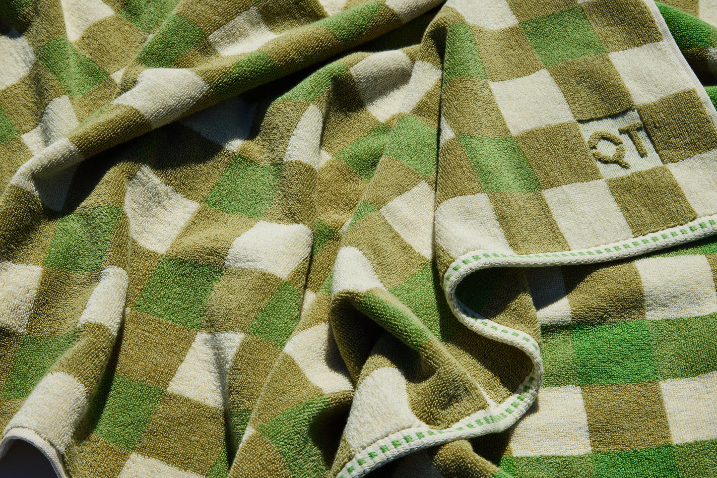Green and beige checkered towel with 'QT' logo