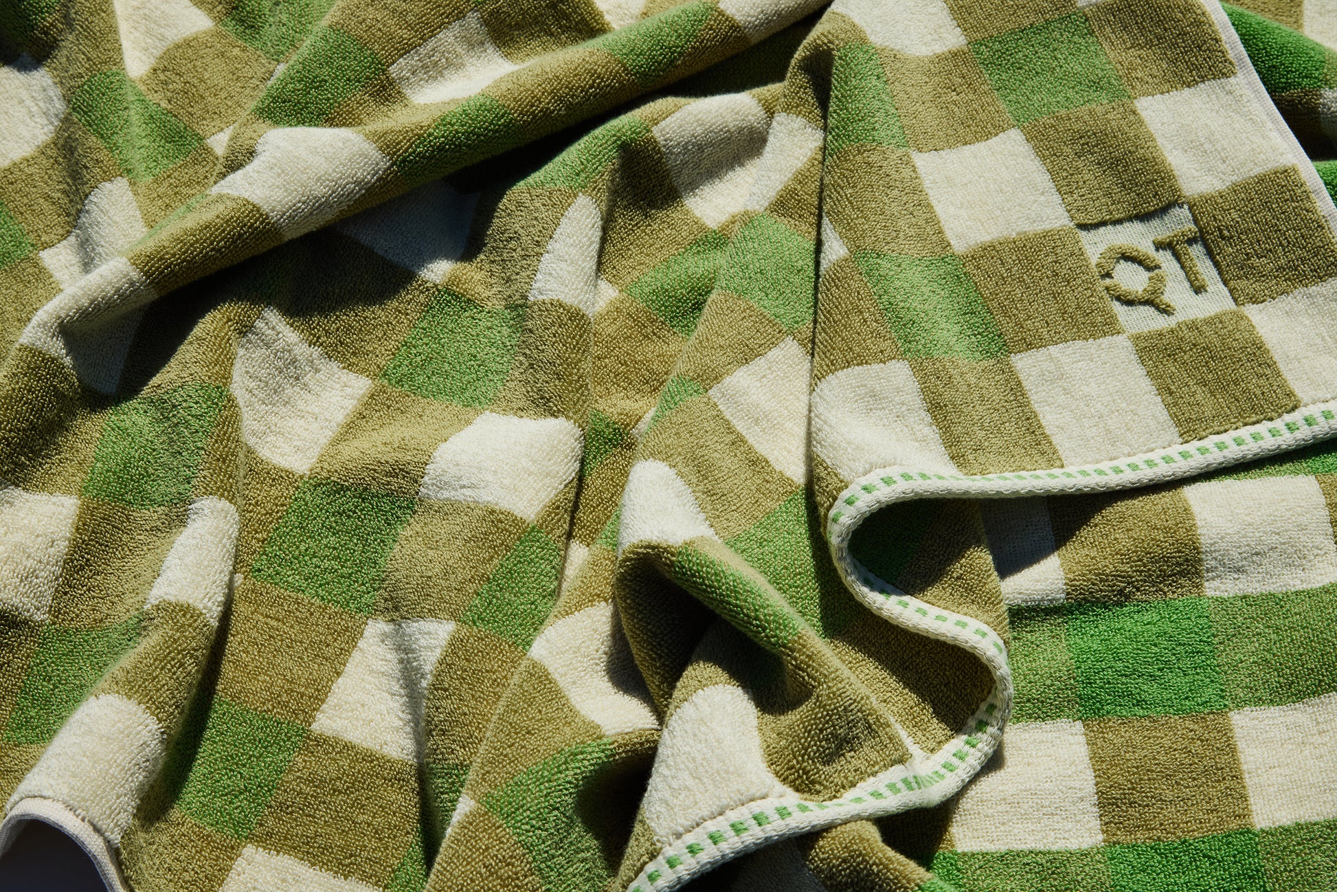 Green and beige checkered towel with 'QT' logo