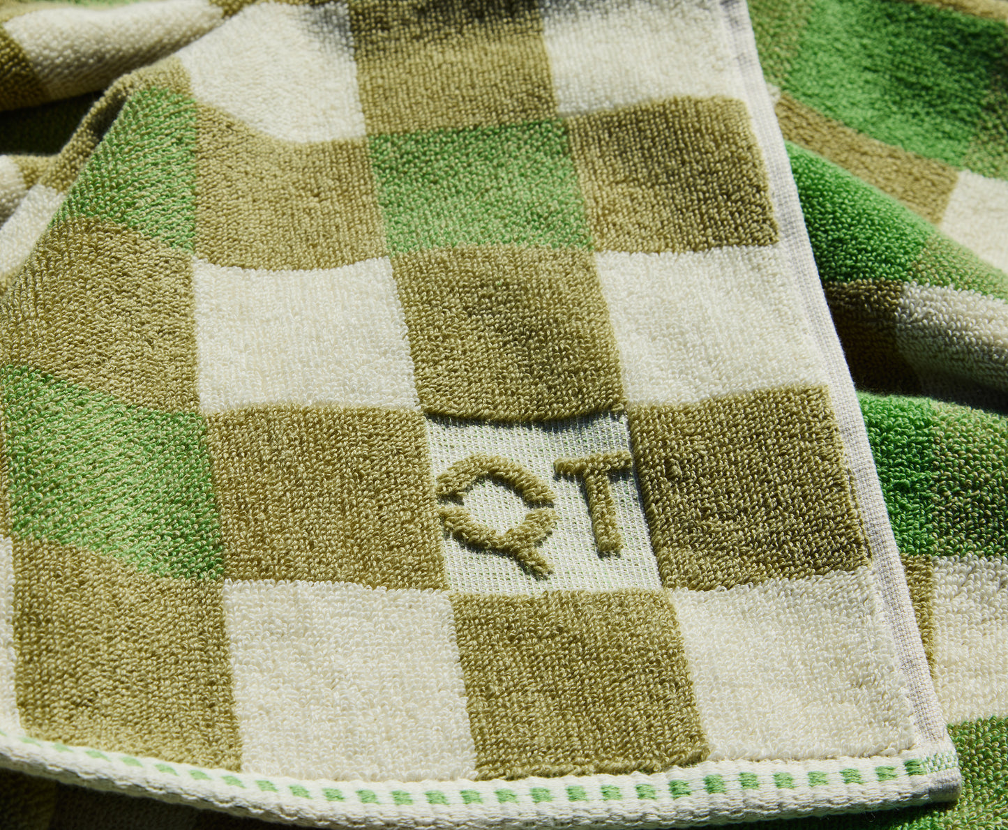 Checkered towel with 'QT' logo on a green and white background
