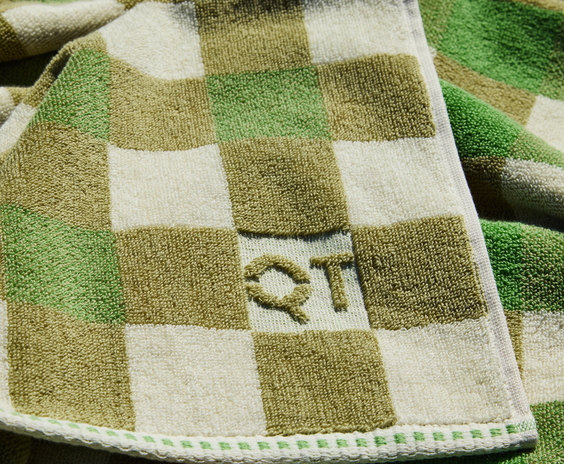Checkered towel with 'QT' logo on a green and white background