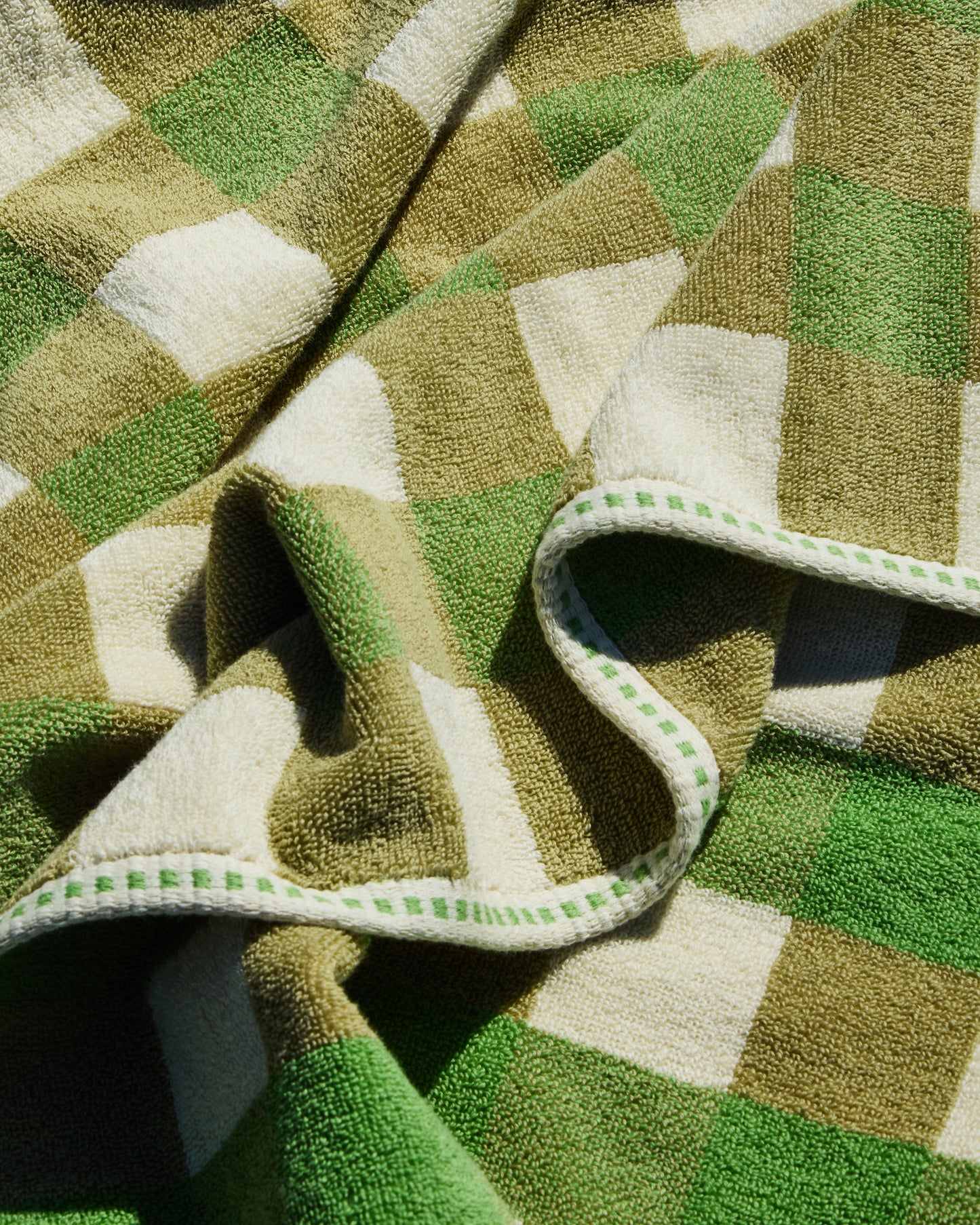 Close-up of a green and beige checkered towel with a folded edge.