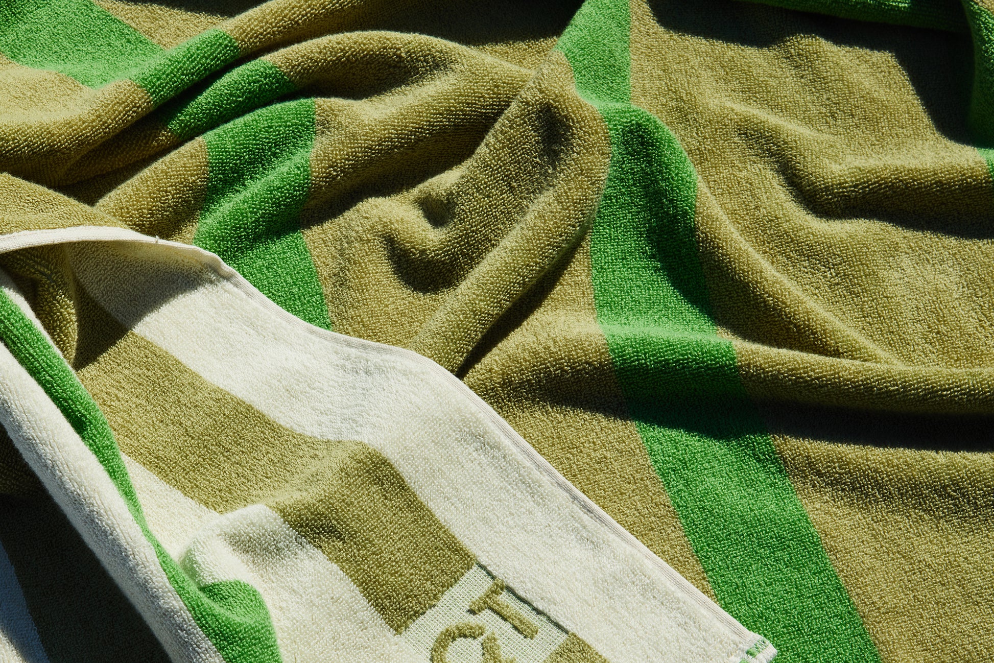 Green and cream striped, reversible  towel draped on floor.