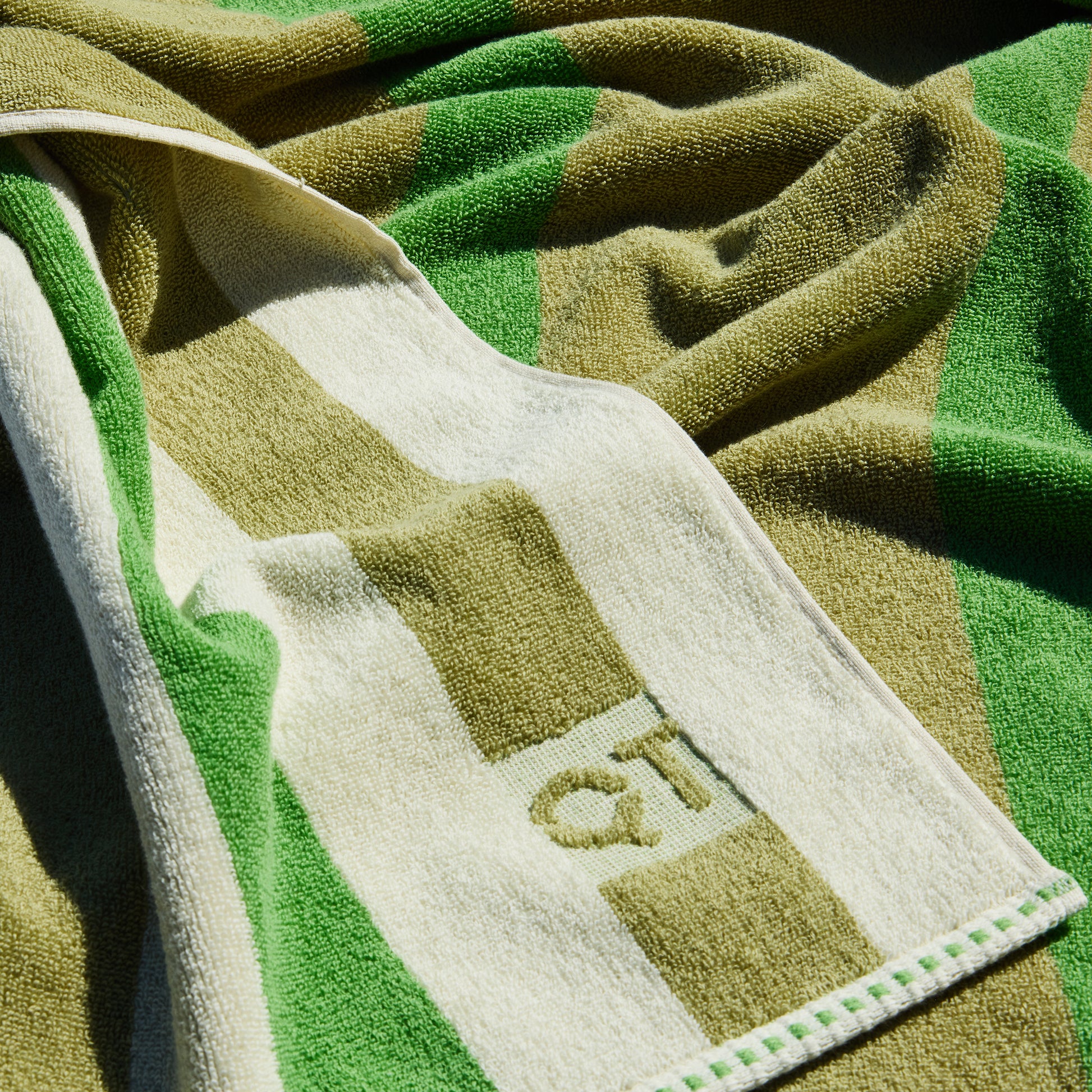Green and beige towel with 'QT' branding