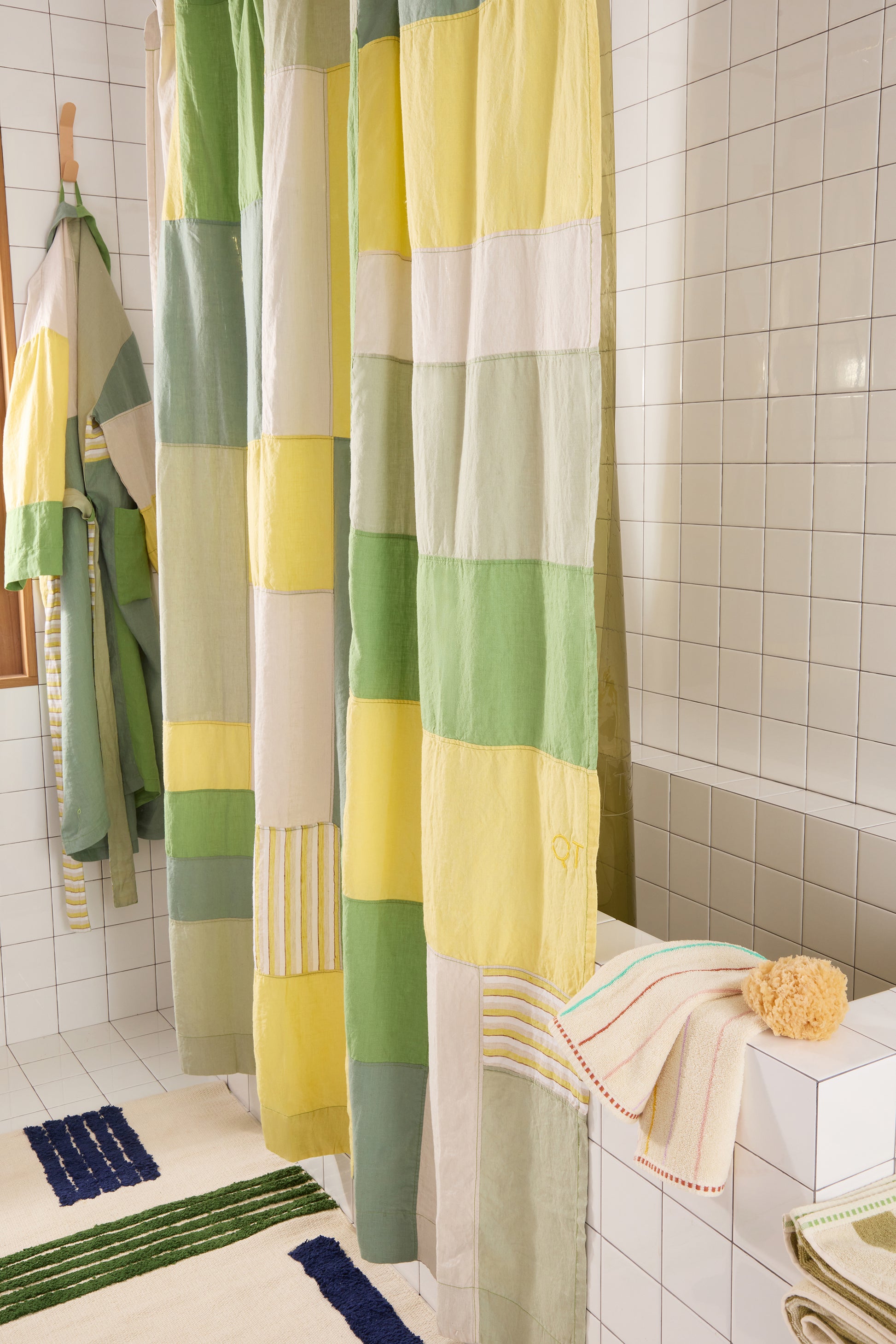 Colorful patchwork shower curtain in a bathroom setting with towels and bath mats.
