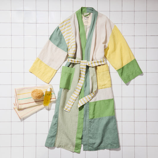 Green and yellow bathrobe with striped towel on a tiled floor