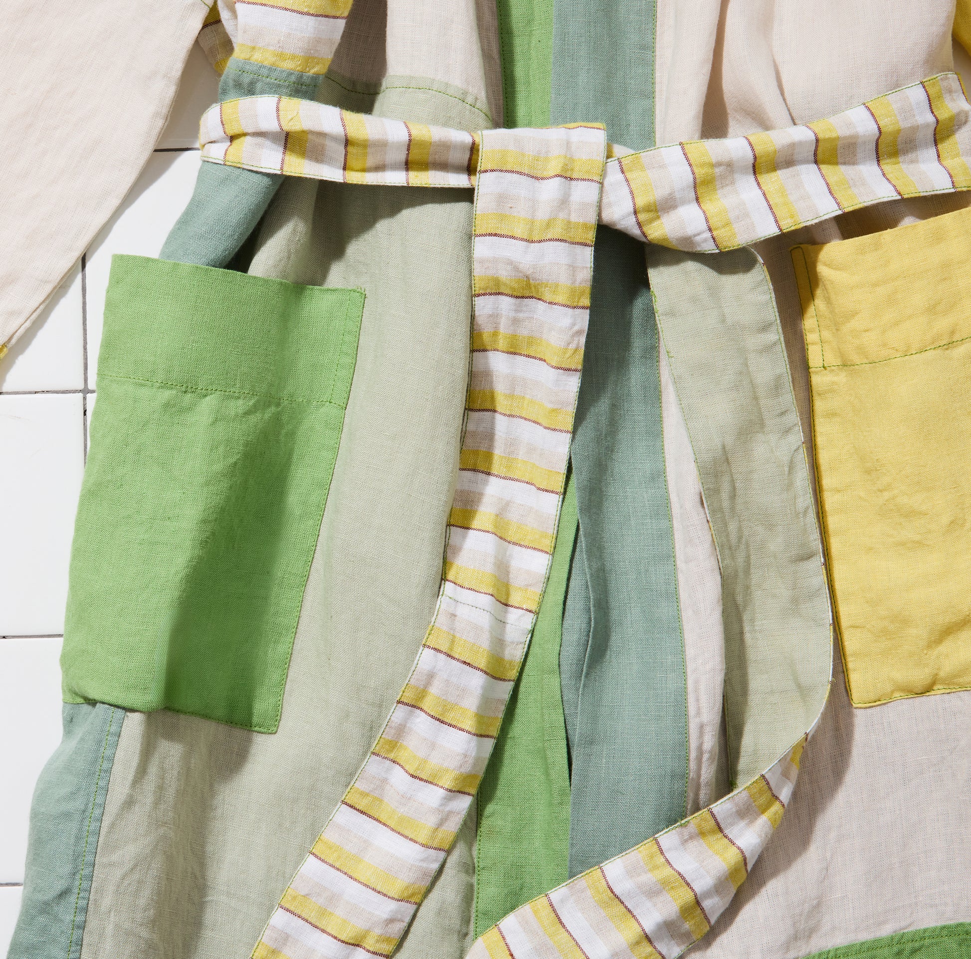 Cropped in photo of green and yellow linen bathrobe with striped belt. 