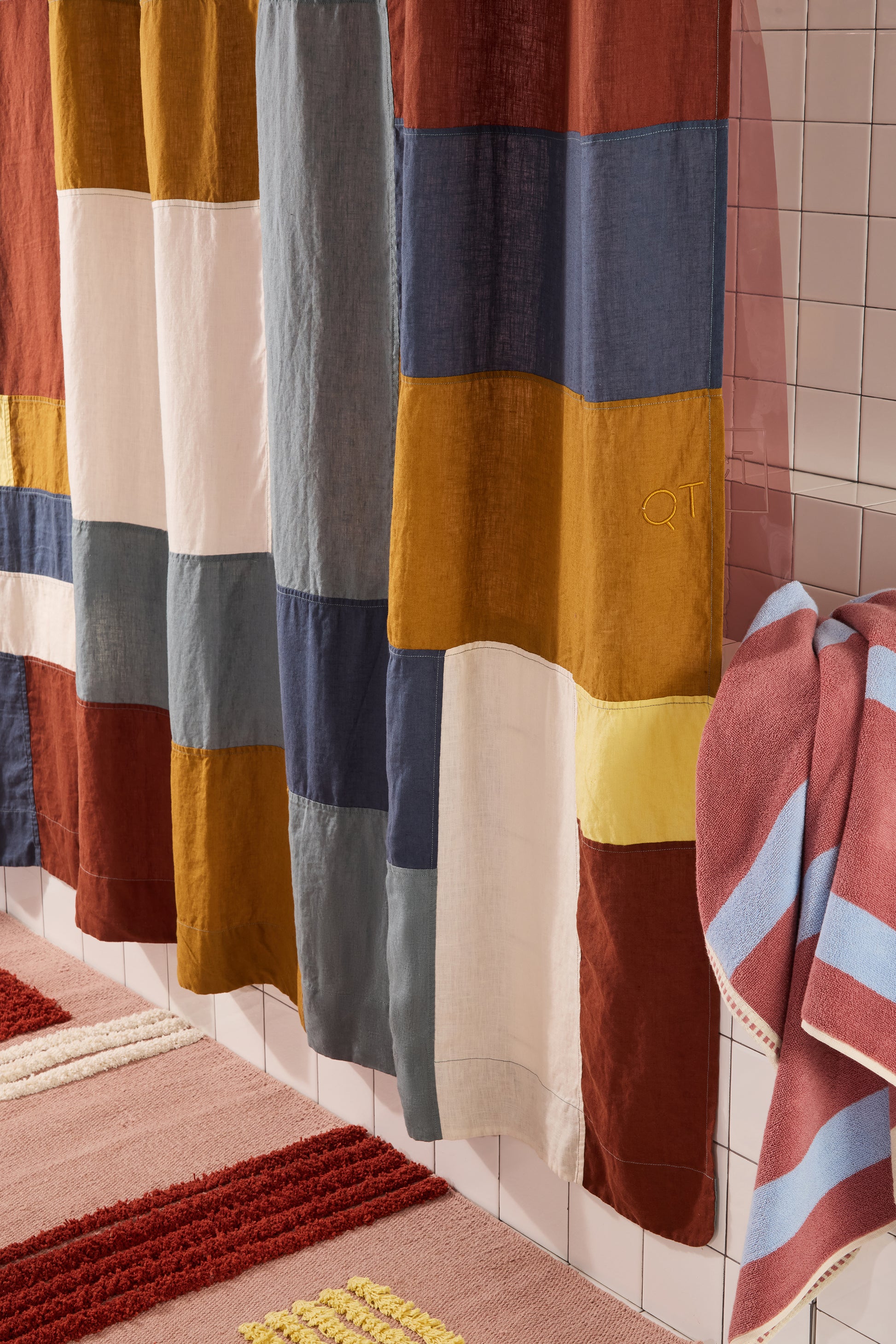multicolor linen curtain with towel and rug in white bathroom.