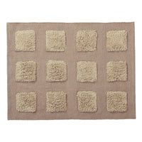 A rectangular bath rug with a textured taupe-brown base and a grid of twelve raised, shaggy squares.
