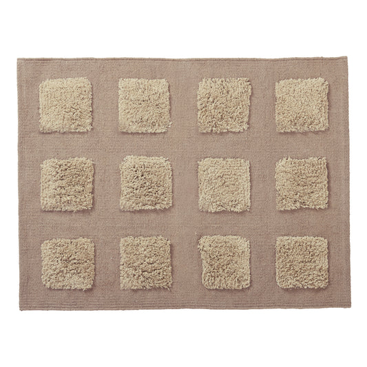 A rectangular bath rug with a textured taupe-brown base and a grid of twelve raised, shaggy squares.