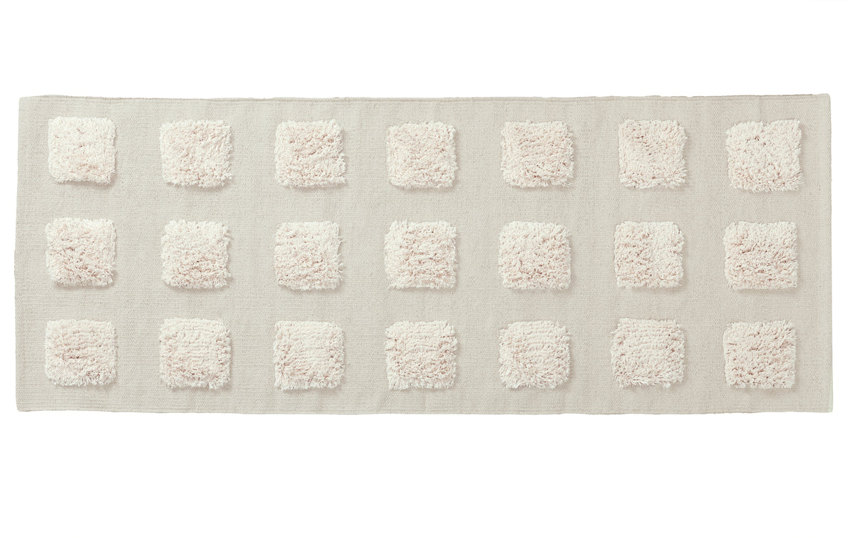 cream textured rectangular bath rug on a white background. 